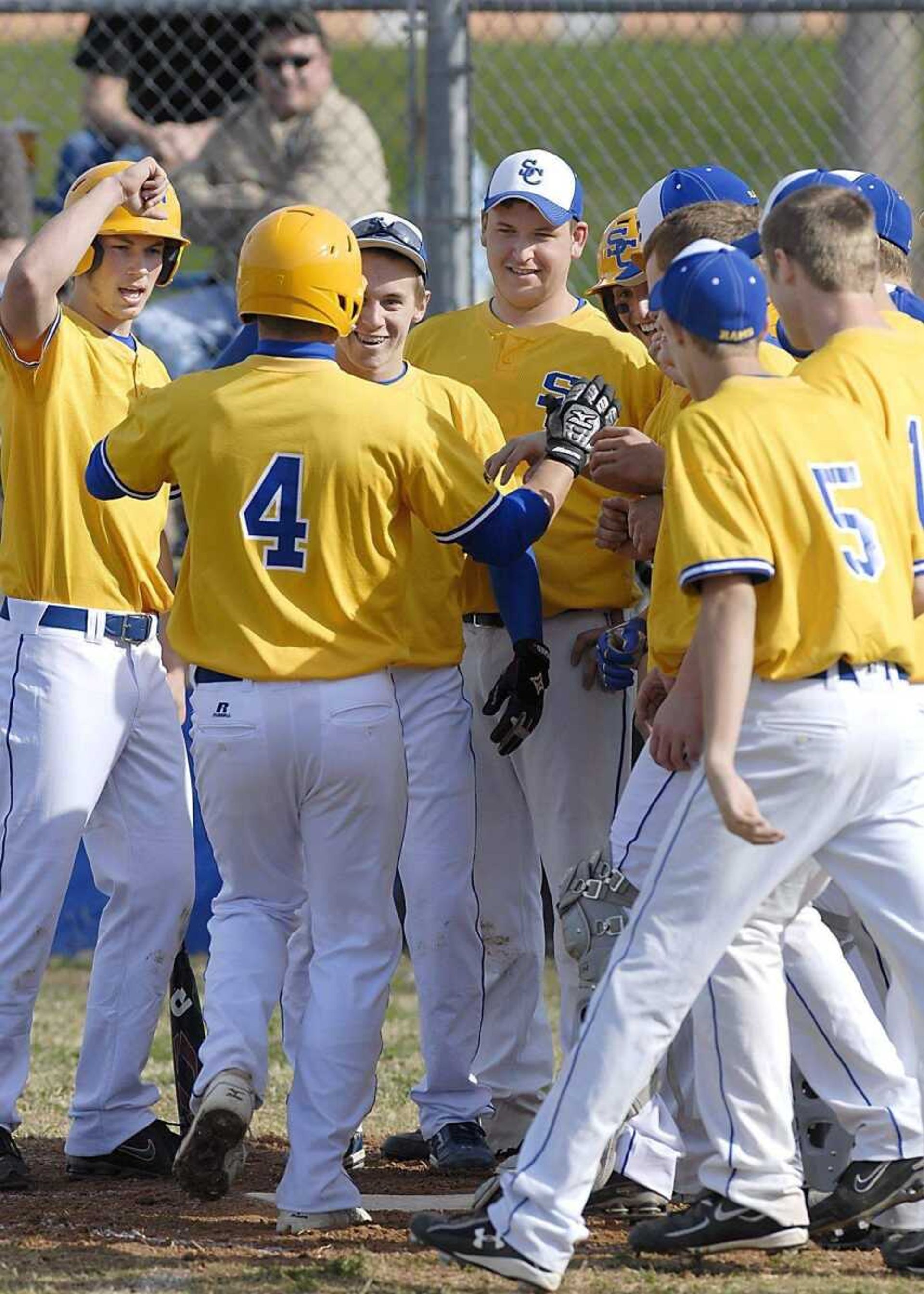 TOP: Jackson's Bobby Clark hits a grounder during Monday's game. ABOVE: Scott City players congratulate Shae Simmons on his first-inning home run. RIGHT: Jackson's Caleb Hosey delivers a pitch.