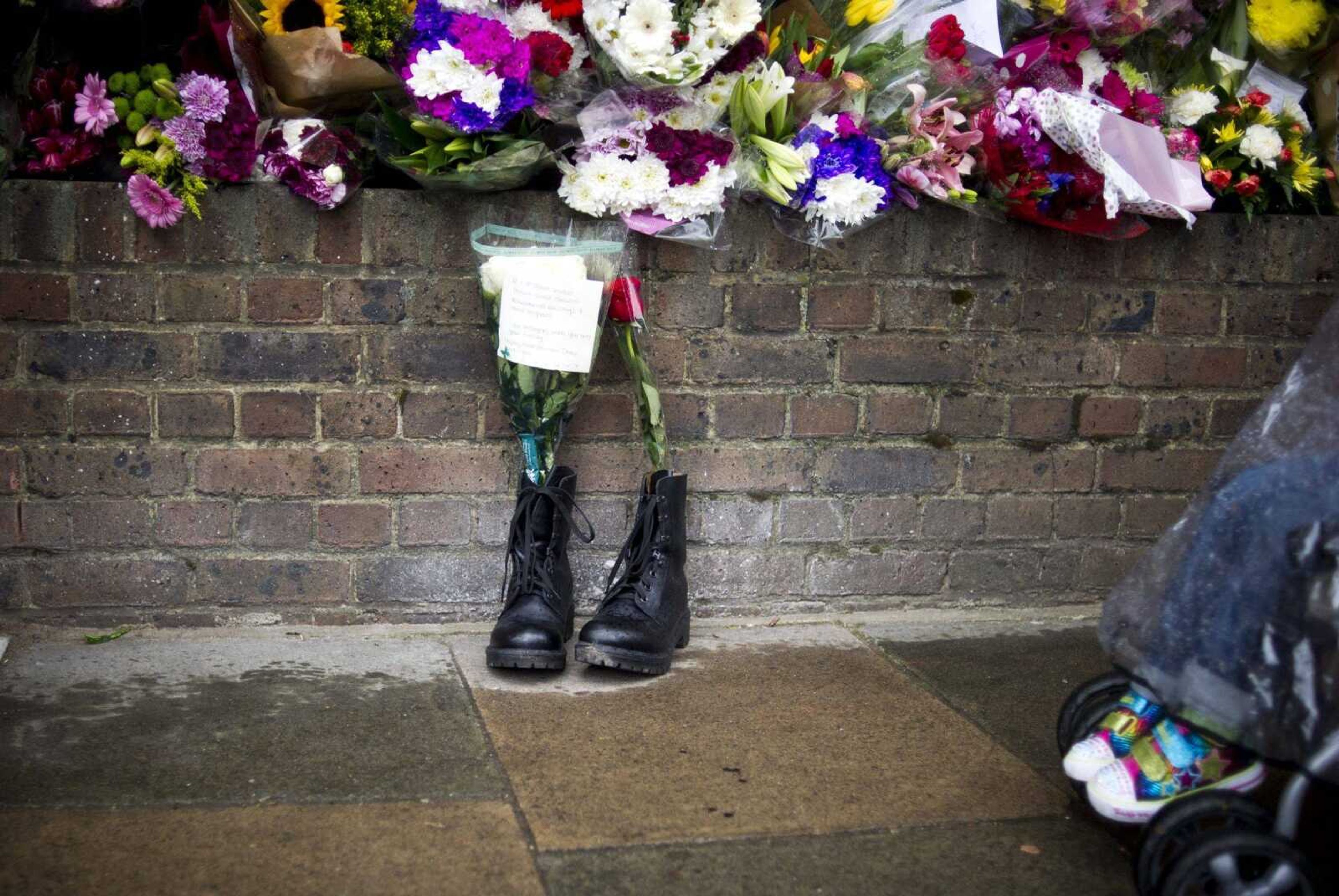 Military boots are laid in tribute outside the Woolwich Barracks on Friday in London in response to the bloody attack Wednesday when a British soldier was killed in the nearby street. (Bogdan Maran ~ Associated Press)