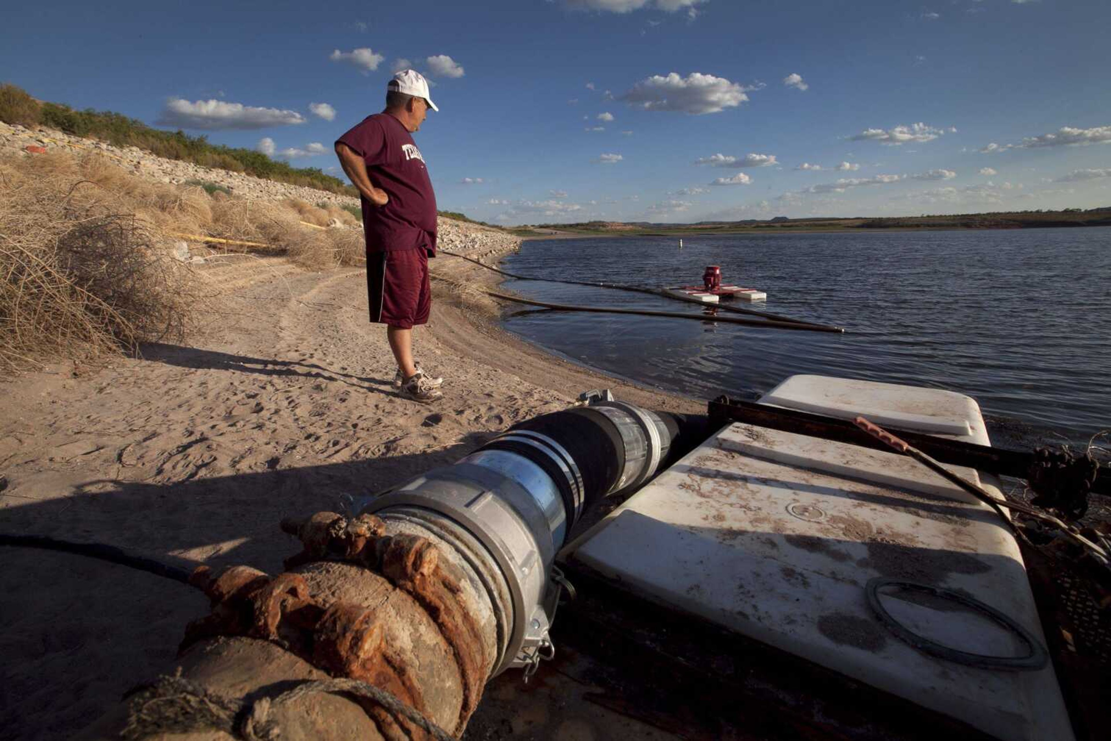 Eddie Ray Roberts, superintendent of the Robert Lee, Texas, waste and water department, looks toward the water pump that sits just feet away from the water line Aug. 7 at Lake E.V. Spence. The pump that was purchased just weeks ago cost the city $30,000, according to Roberts. The pump is feeding water from Spence to the Mount Creek Reservoir, on the opposite side of the small rural town, nearly 1.3 million gallons of water daily. Every few days, Roberts or members of his small department must relocate the pump because of the receding water line in this drought-stricken region that endures triple-digit heat daily. (Tony Gutierrez ~ Associated Press)