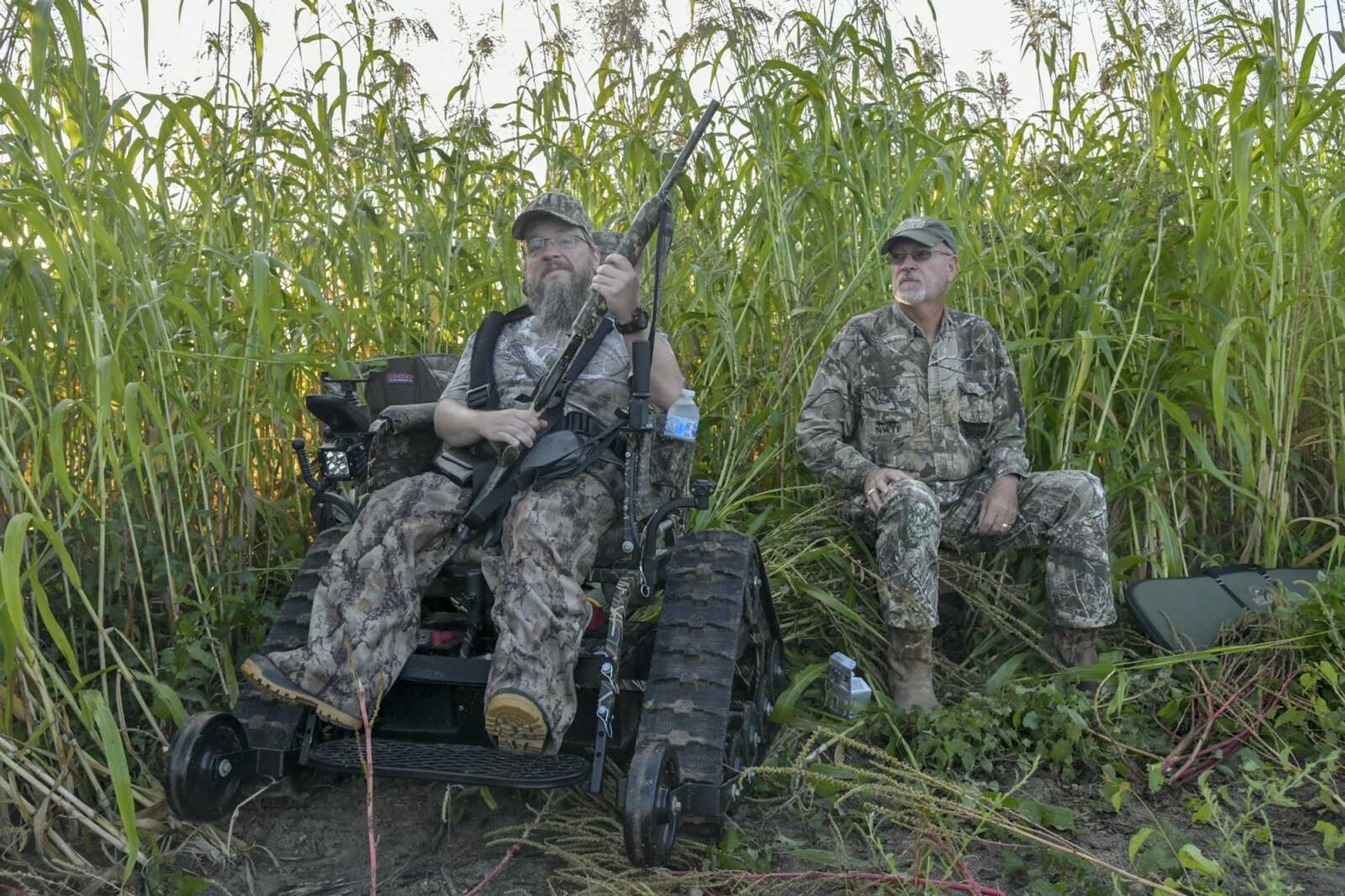 Gabe Glastetter and Paul Strickland sit near the edge of tall grass, on the look out for doves, during MDC's Mobility Impaired Dove Hunt at the Ten Mile Pond in East Prairie Wednesday Sept. 1, 2021. The pair met during the hunt, which provides a volunteer guide from the National Wild Turkey Federation for the hunter.