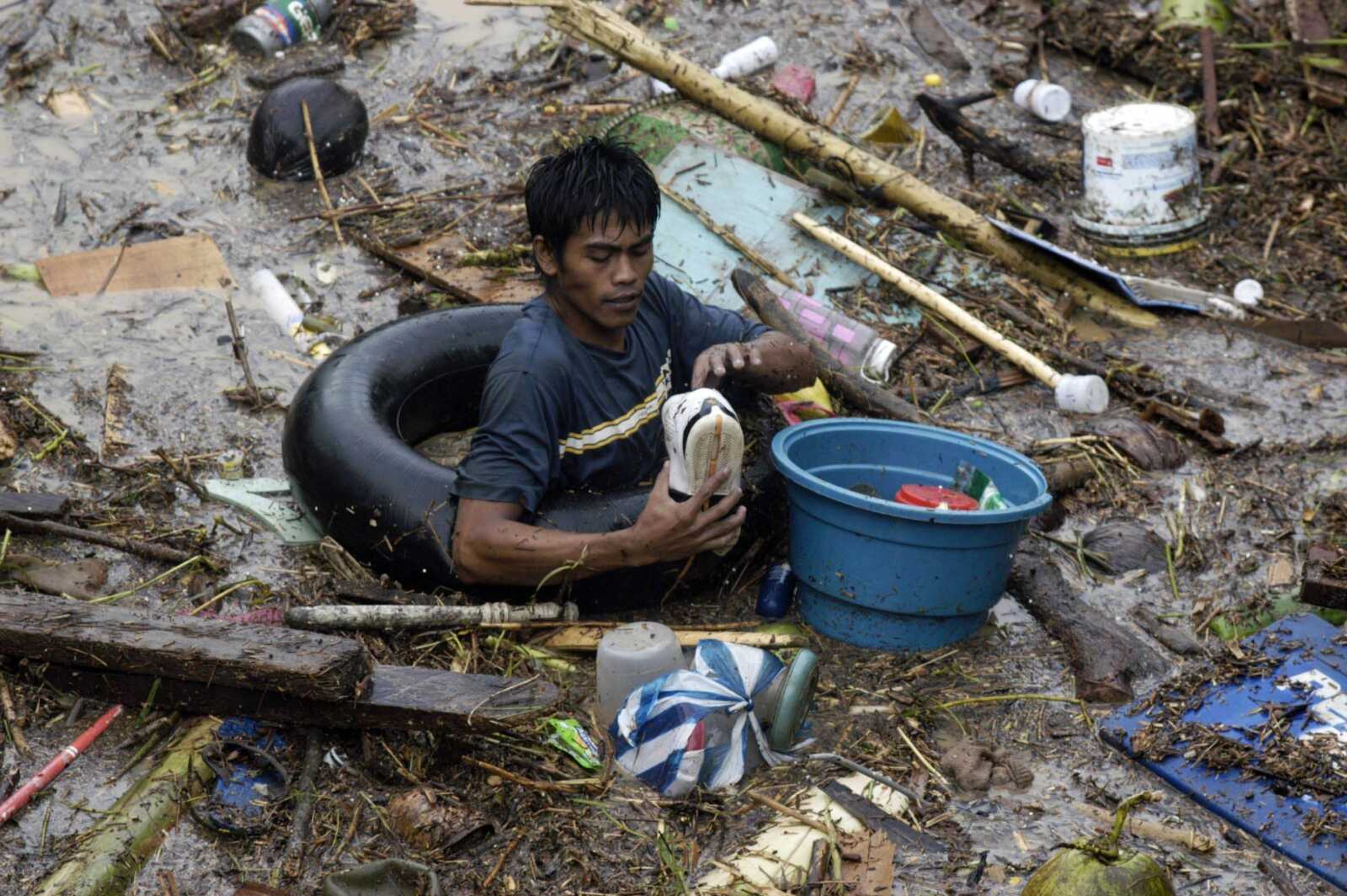 A resident rummages through debris Saturday following a flash flood that inundated Cagayan de Oro, Philippines. A tropical storm triggered flash floods in the southern Philippines, killing scores of people and missing more. Mayor Lawrence Cruz of nearby Iligan said the coast guard and other rescuers were scouring the waters off his coastal city for survivors or bodies that may have been swept to the sea by a swollen river. (Froilan Gallardo ~ Associated Press)