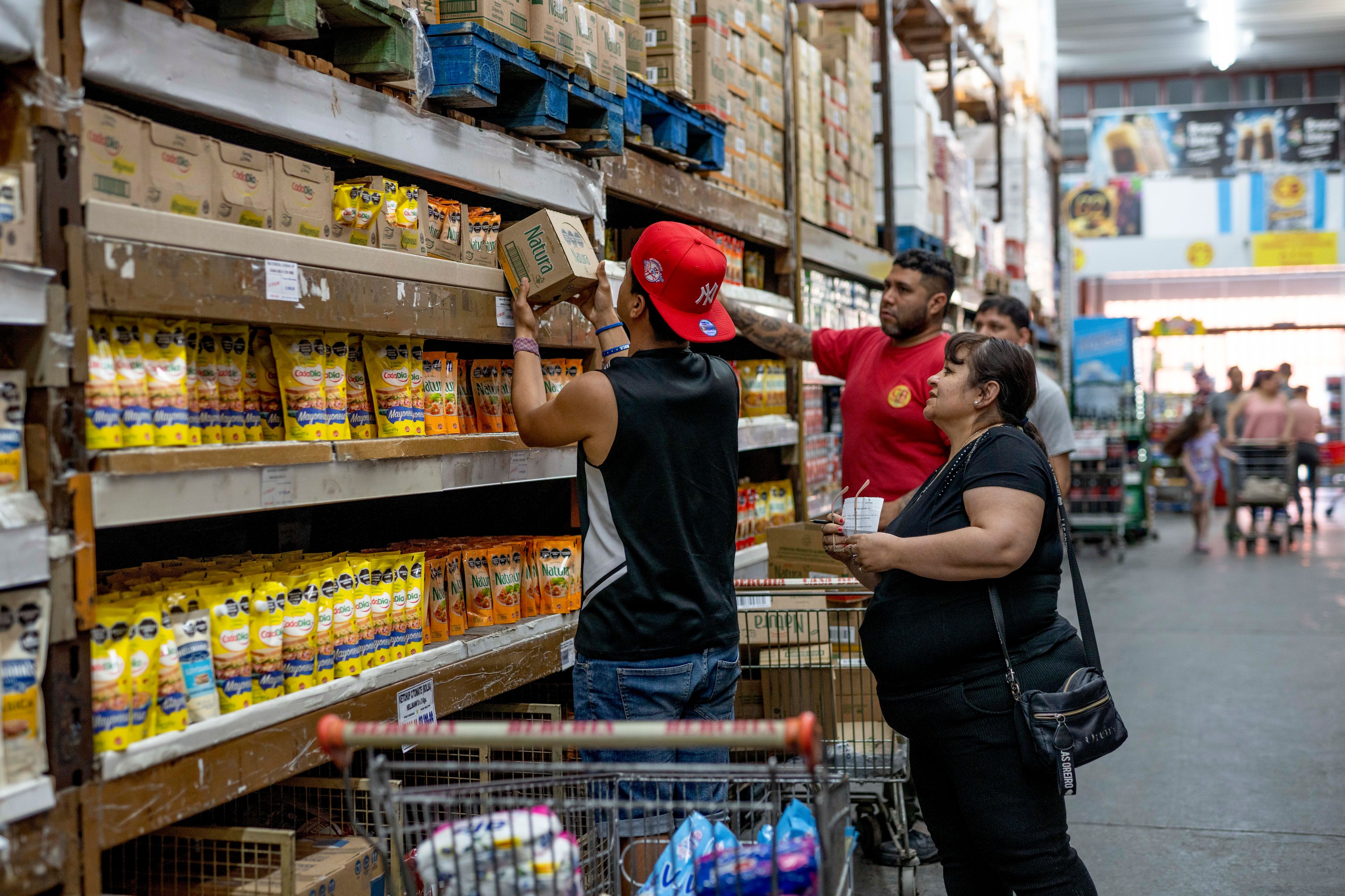 People buy groceries at a supermarket that accepts "chachos" currency in La Rioja, Argentina, Monday, Sept. 23, 2024. In response to slashed federal budgets to provinces, La Rioja is printing a new emergency tender called "chachos" to pay state workers and spur the economy. (AP Photo/Natalia Diaz)