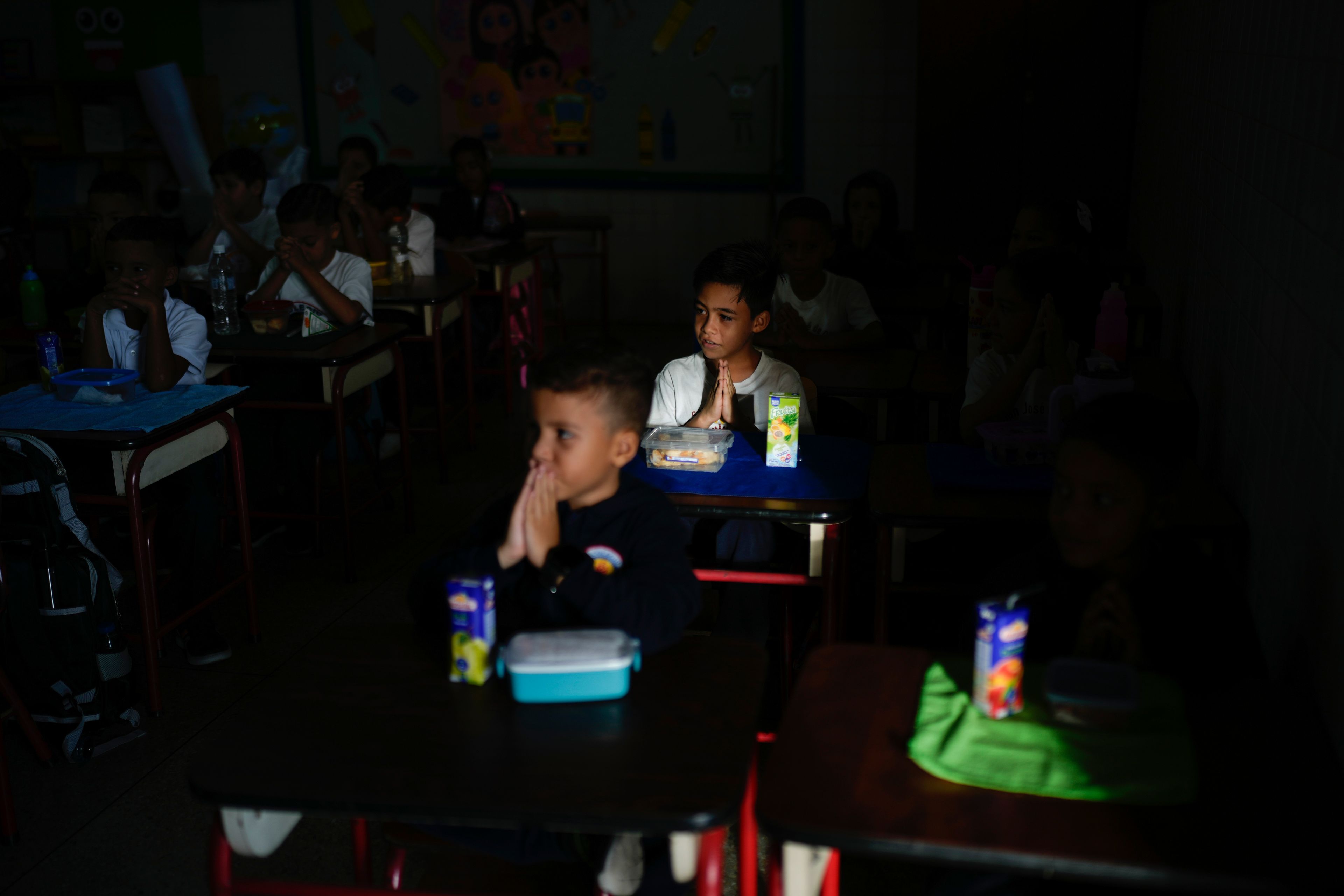 Students pray before eating breakfast on the first day back to class, at a private school in Caracas, Venezuela, Monday, Sept. 30, 2024. (AP Photo/Ariana Cubillos)