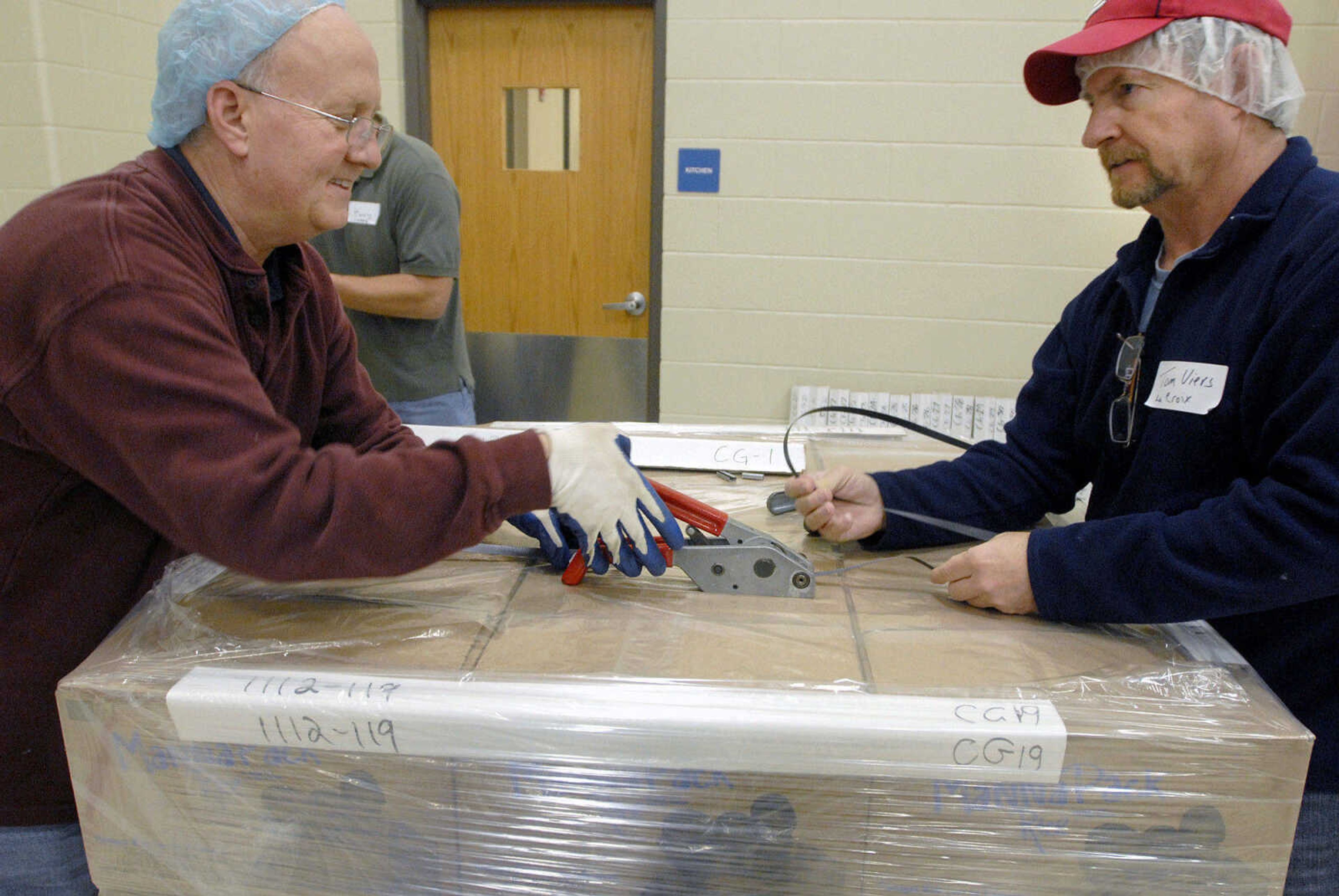 LAURA SIMON ~ lsimon@semissourian.com
Tom Muir, left, and Tom Viers seal a pallet of MannaPack Rice meals Friday night, Dec. 9, 2011 during the Feed My Starving Children Mobilepack event at Shawnee Park center in Cape Girardeau.