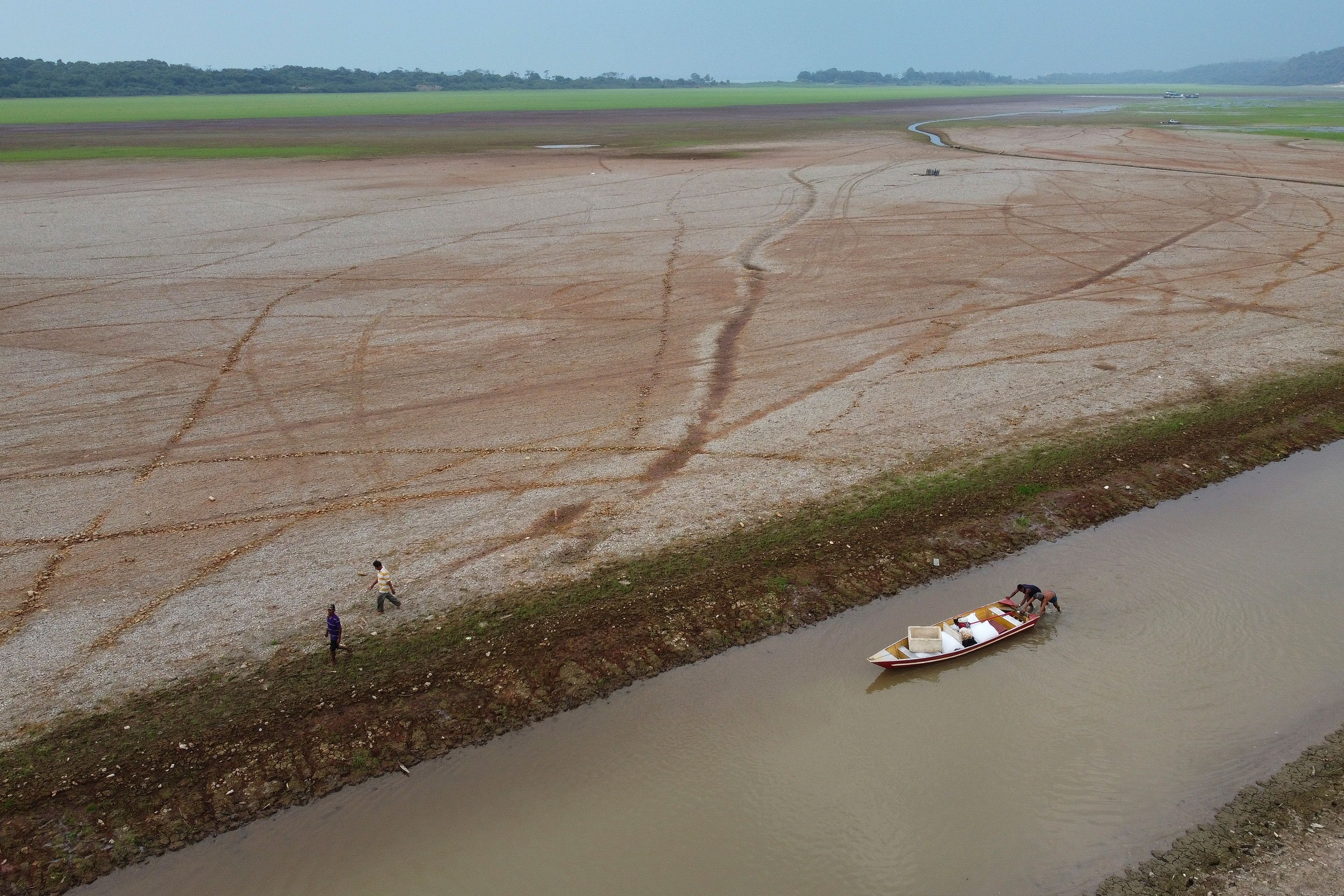 FILE - Fishermen push a boat in the Aleixo Lake amid a drought in Manaus, Amazonas state, Brazil, Sept. 24, 2024. (AP Photo/Edmar Barros, File)