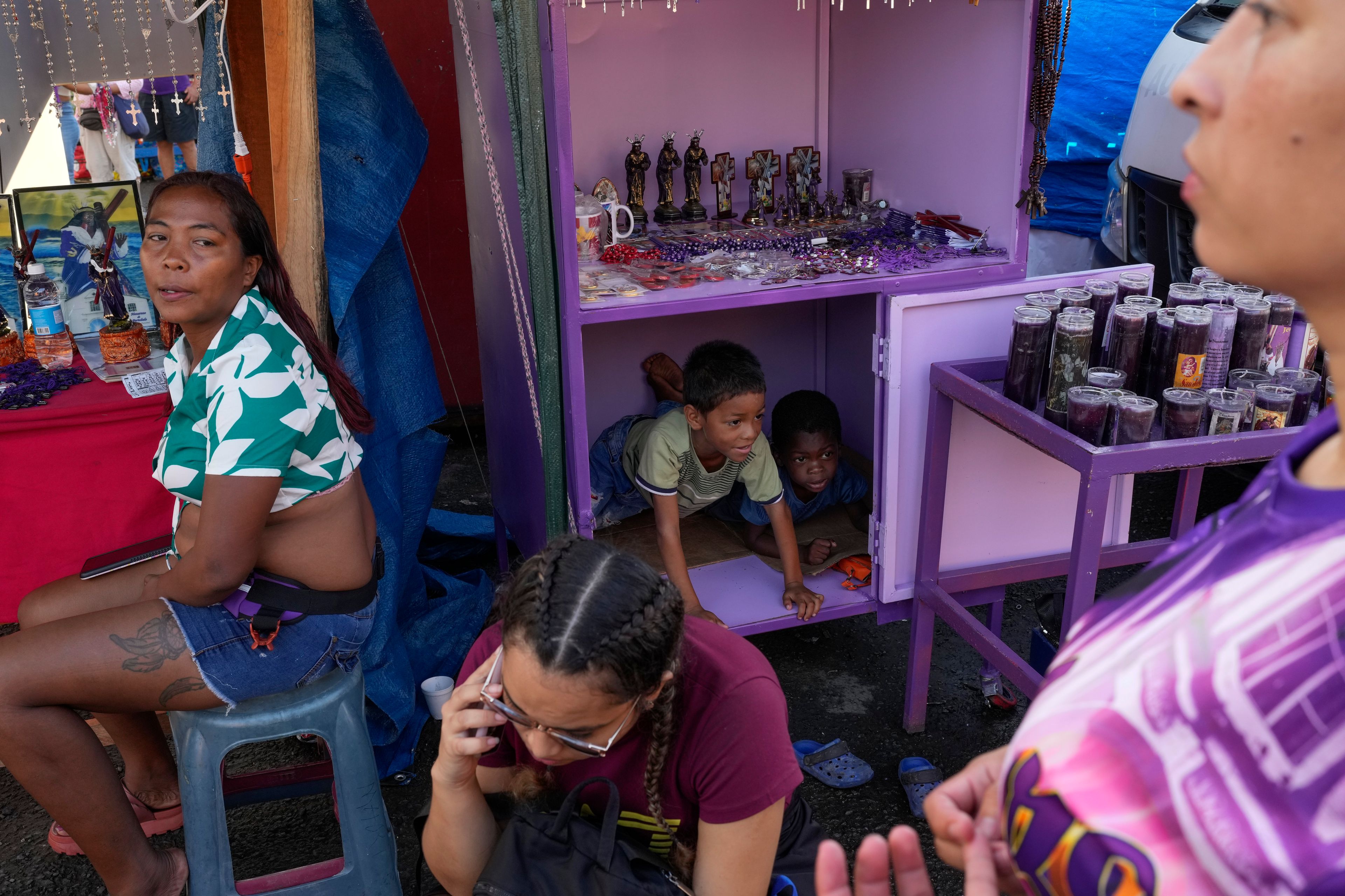 Children play at a vendor's booth outside San Felipe Catholic church in Portobelo, Panama, Monday, Oct. 21, 2024, during a festival celebrating the iconic statue that was found on the shore in 1658. (AP Photo/Matias Delacroix)