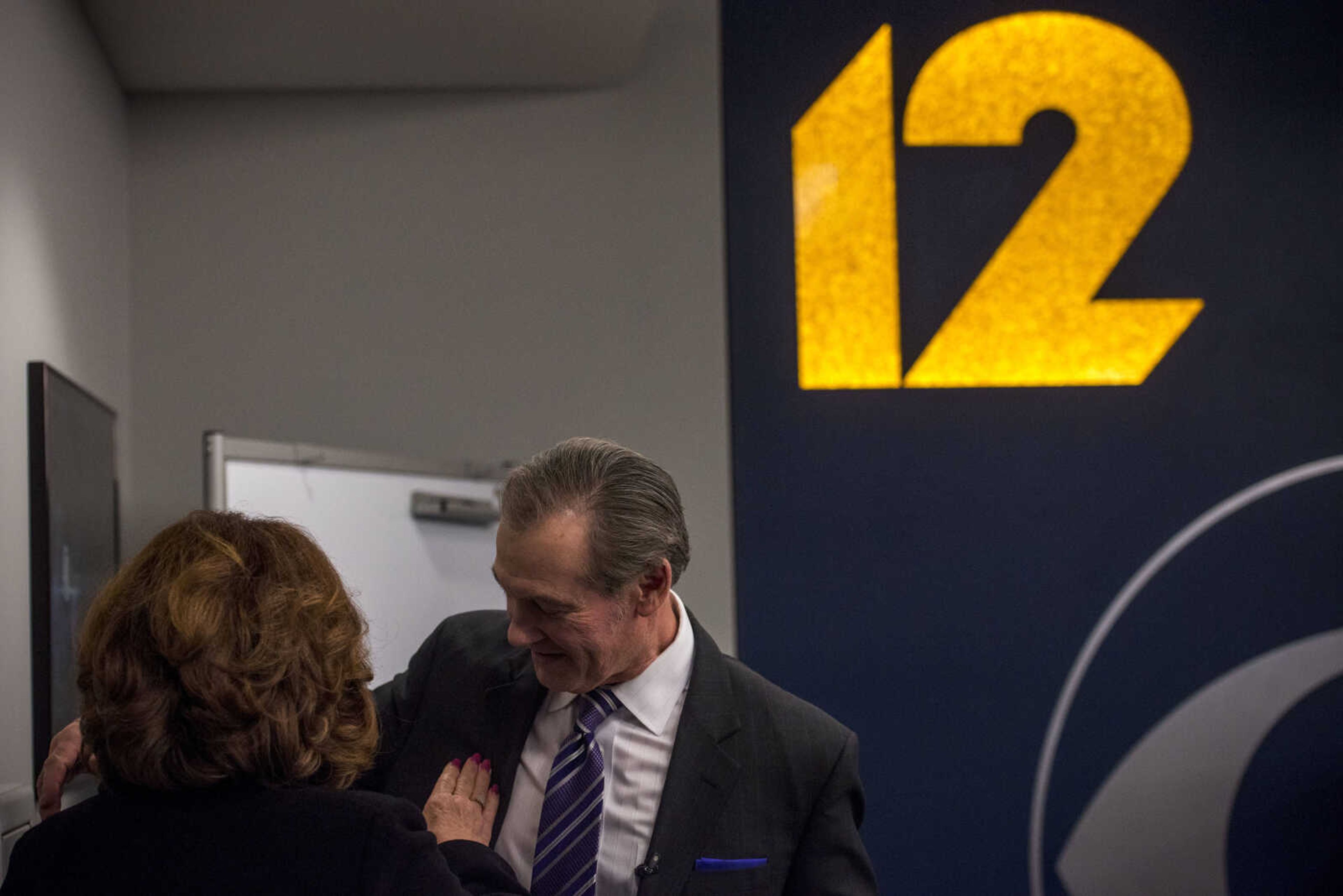 Jim Burns's wife of 41 years, Lisa, brushes off her husband's lapel before he returns to the KFVS news desk during Burns's final morning show before retirement Friday, Dec. 21, 2018.