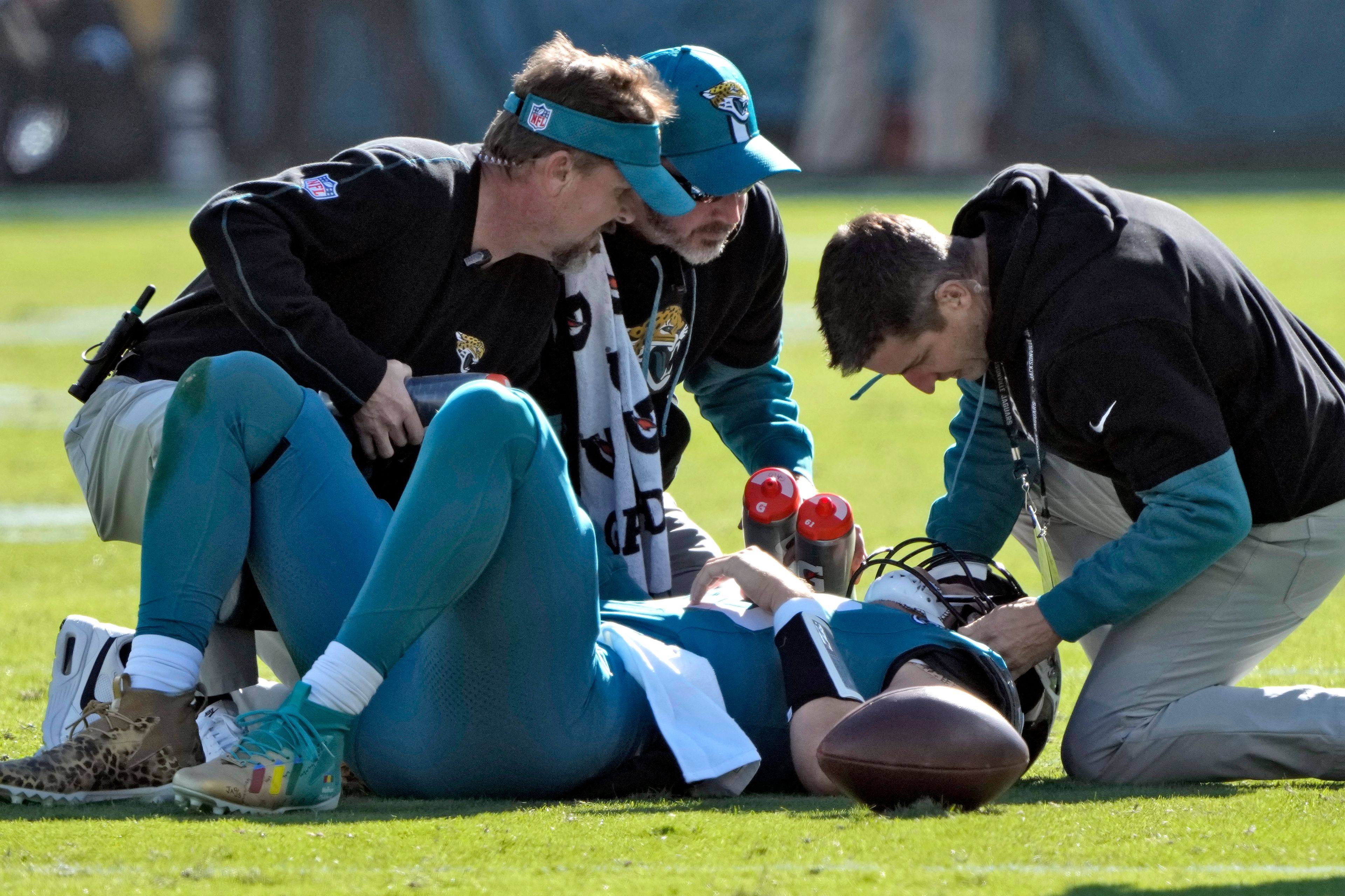 Jacksonville Jaguars quarterback Trevor Lawrence (16) is looked at by trainers after a late hit by Houston Texans linebacker Azeez Al-Shaair (0) during the first half of an NFL football game Sunday, Dec. 1, 2024, in Jacksonville, Fla. (AP Photo/John Raoux)