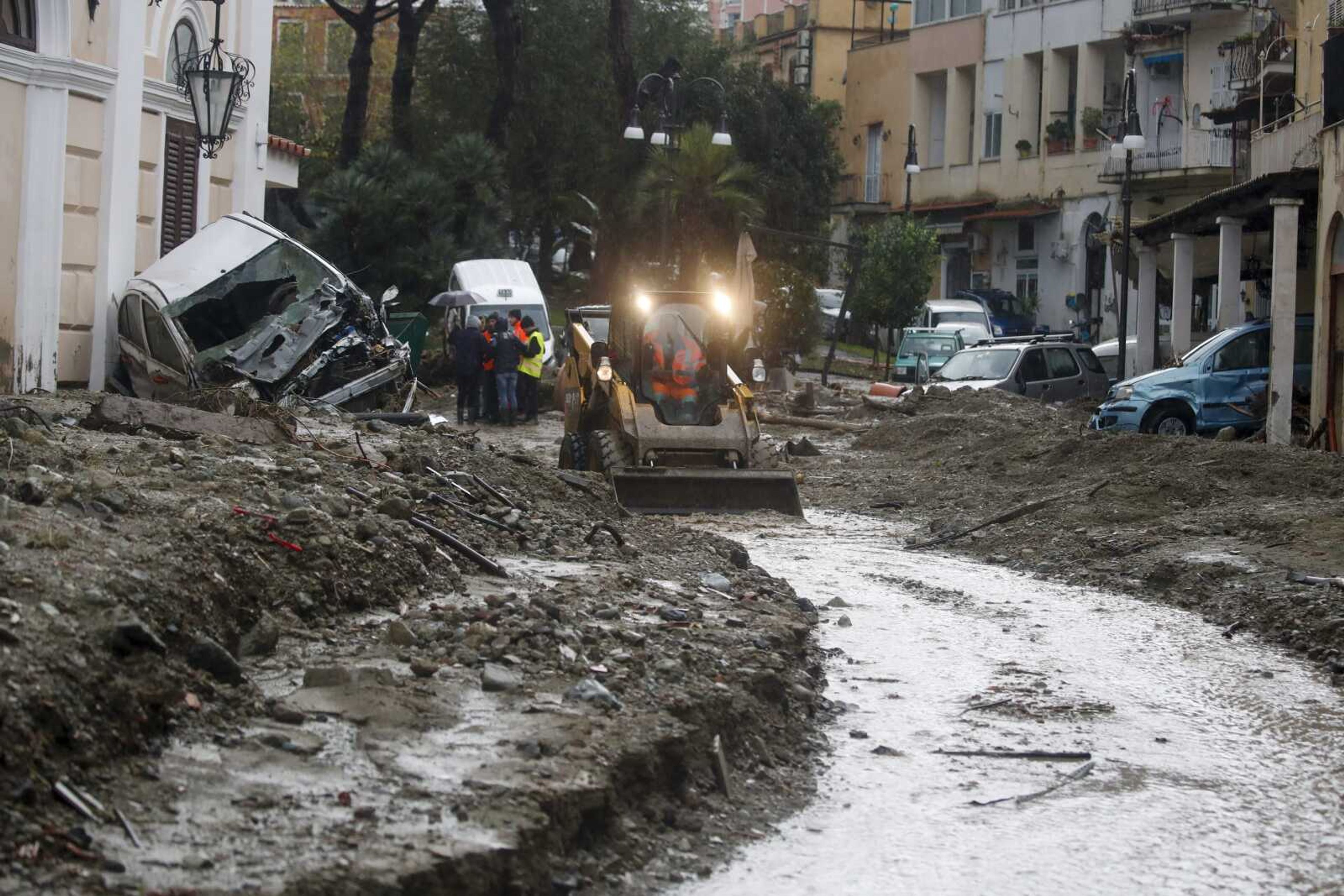 A caterpillar removes mud from a flooded road after heavy rainfall triggered landslides that collapsed buildings and left as many as 12 people missing, Saturday in Casamicciola, Italy.Firefighters worked on rescue efforts as reinforcements were sent from nearby Naples, but encountered difficulties in reaching the island either by motorboat or helicopter because of the weather.