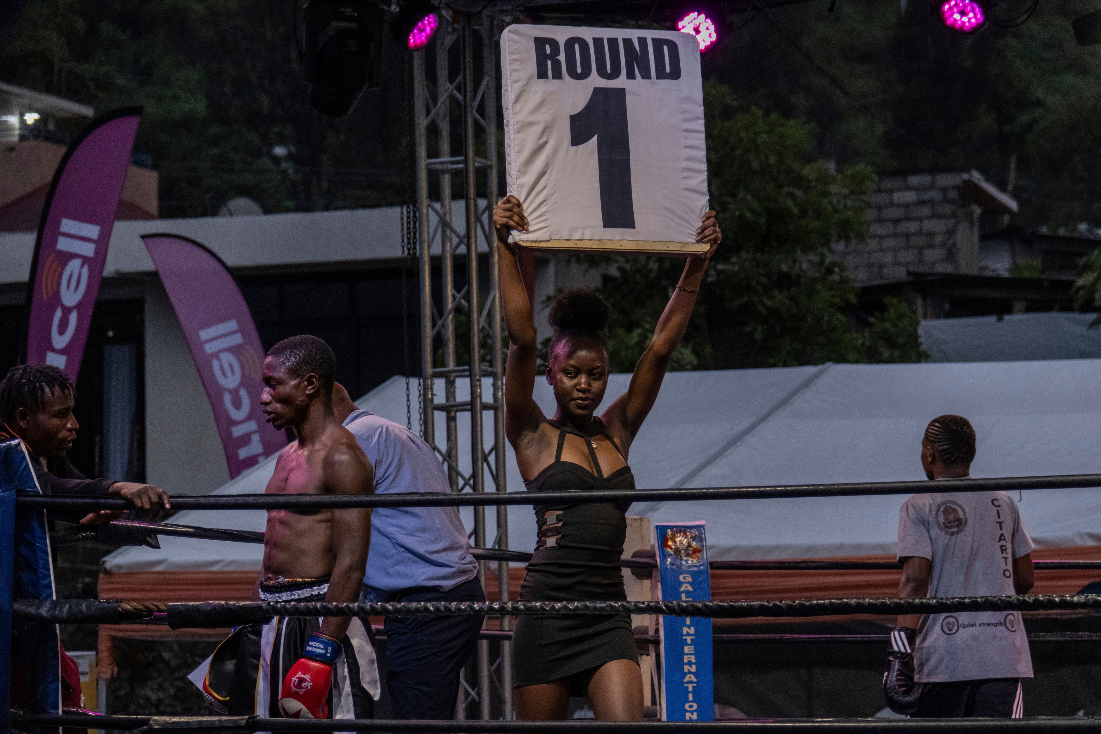 A woman holds the first round sign of boxing competition in which Daniella Mulekets, 20, fight in her first professional boxing match in Goma, Democratic republic of the Congo, Oct. 26 2024 on the 50th anniversary of the "Rumble in the Jungle" fight between Muhammad Ali and George Foreman in Kinshasa. (AP Photo/Moses Sawasawa)