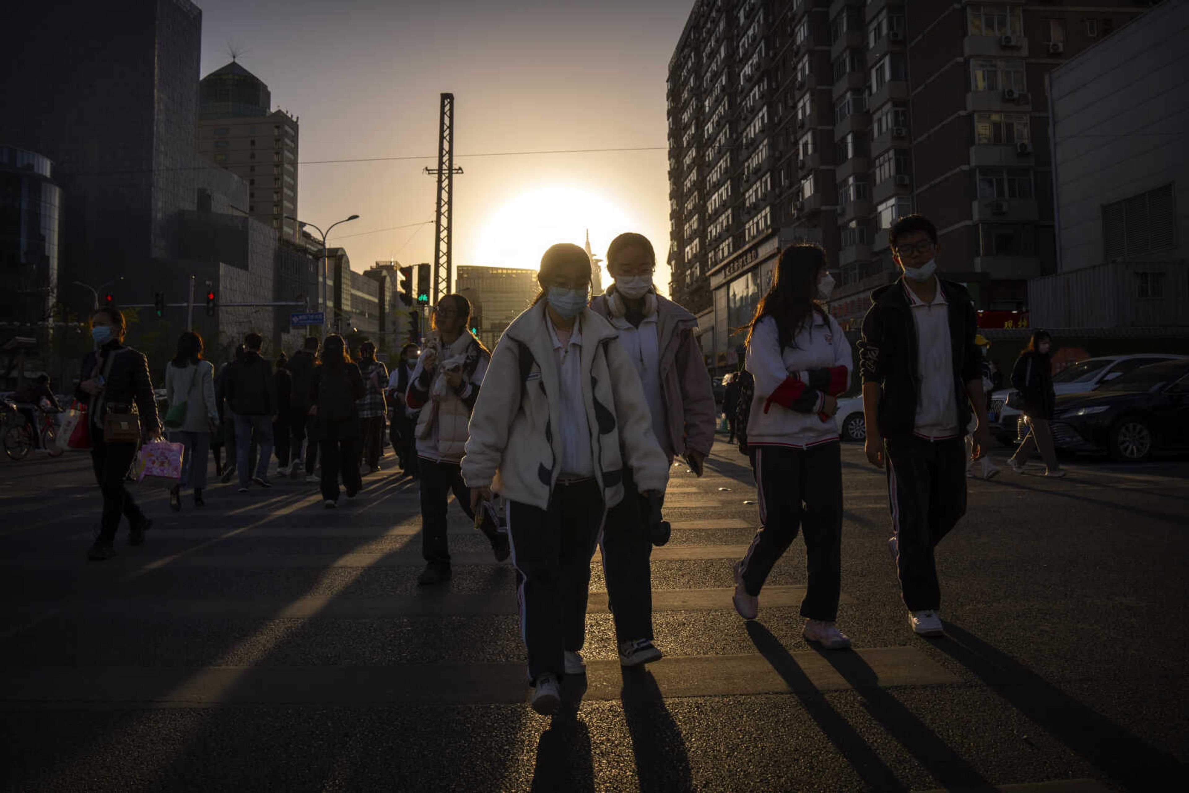 Commuters wearing face masks cross an intersection Friday in Beijing. China, the world's second biggest economy, is expected to grow 5.2% this year, as it rebounds from the end in late 2022 of a draconian zero-COVID policy.