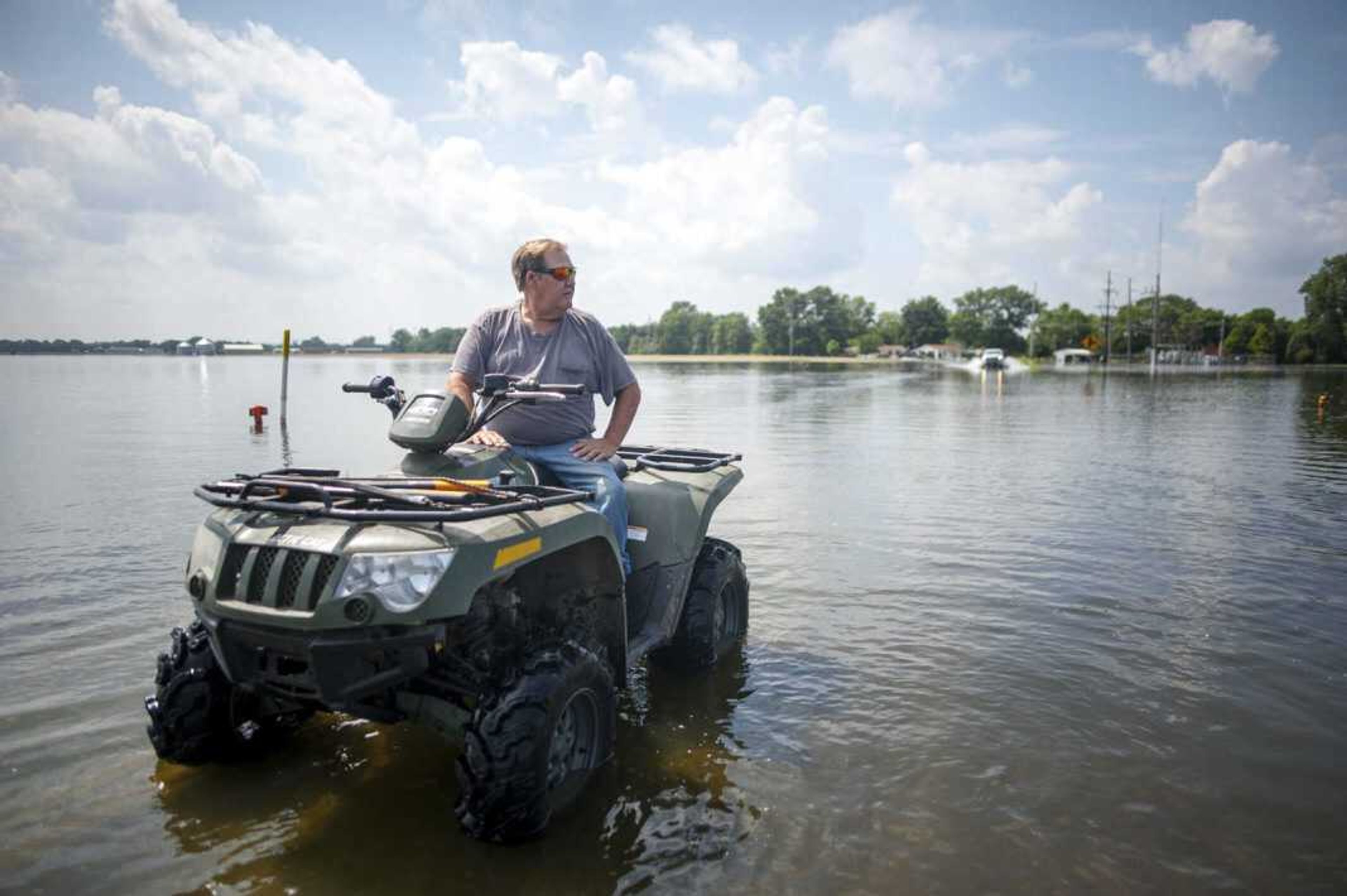 Rick Myers waits for a truck to pass on a flooded stretch of road Saturday in McClure, Illinois. Myers said most people drive too fast through floodwaters and often leave wakes that can undermine levees around houses that would otherwise hold up. "Some people are courteous about it, but others of them, not so much," he said.