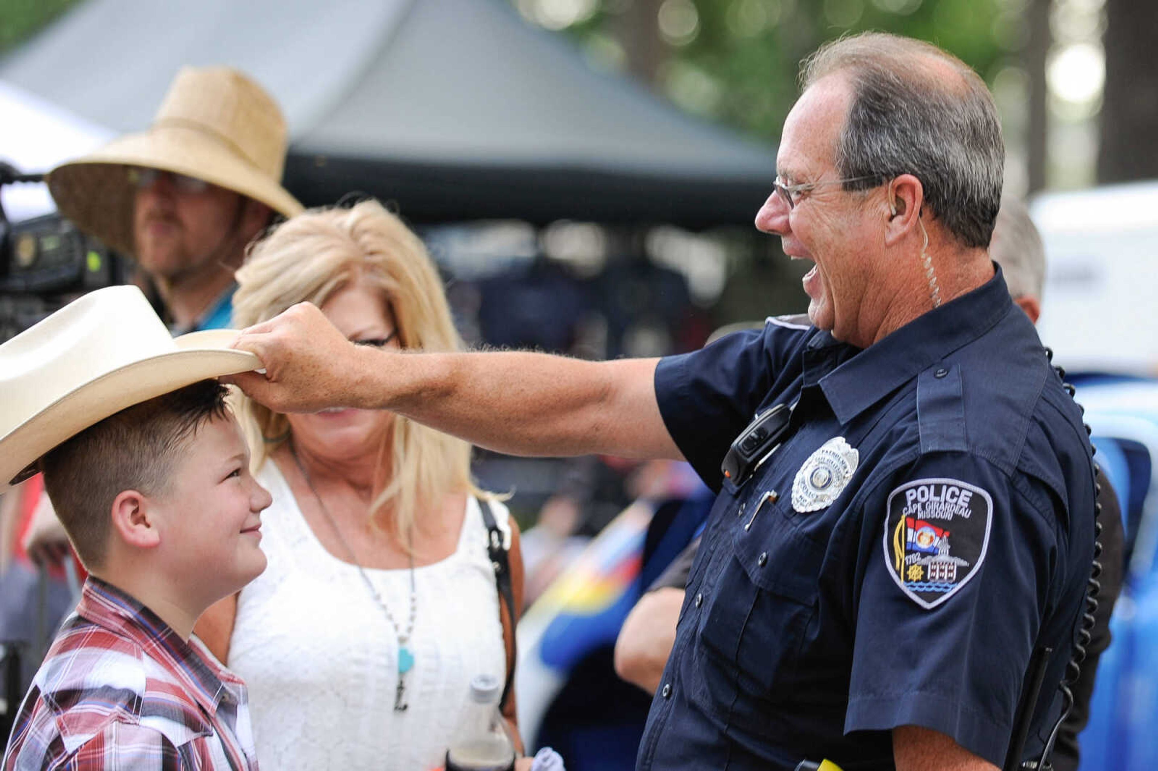 GLENN LANDBERG ~ glandberg@semissourian.com

Officer David Valentine of the Cape Girardeau Police Department shares a laugh as he returns a cowboy hat to Colter Sparkman after trying it on during the Rev'n Rods & Heartland Music Tour stop at Arena Park Tuesday, July 19, 2016 in Cape Girardeau.