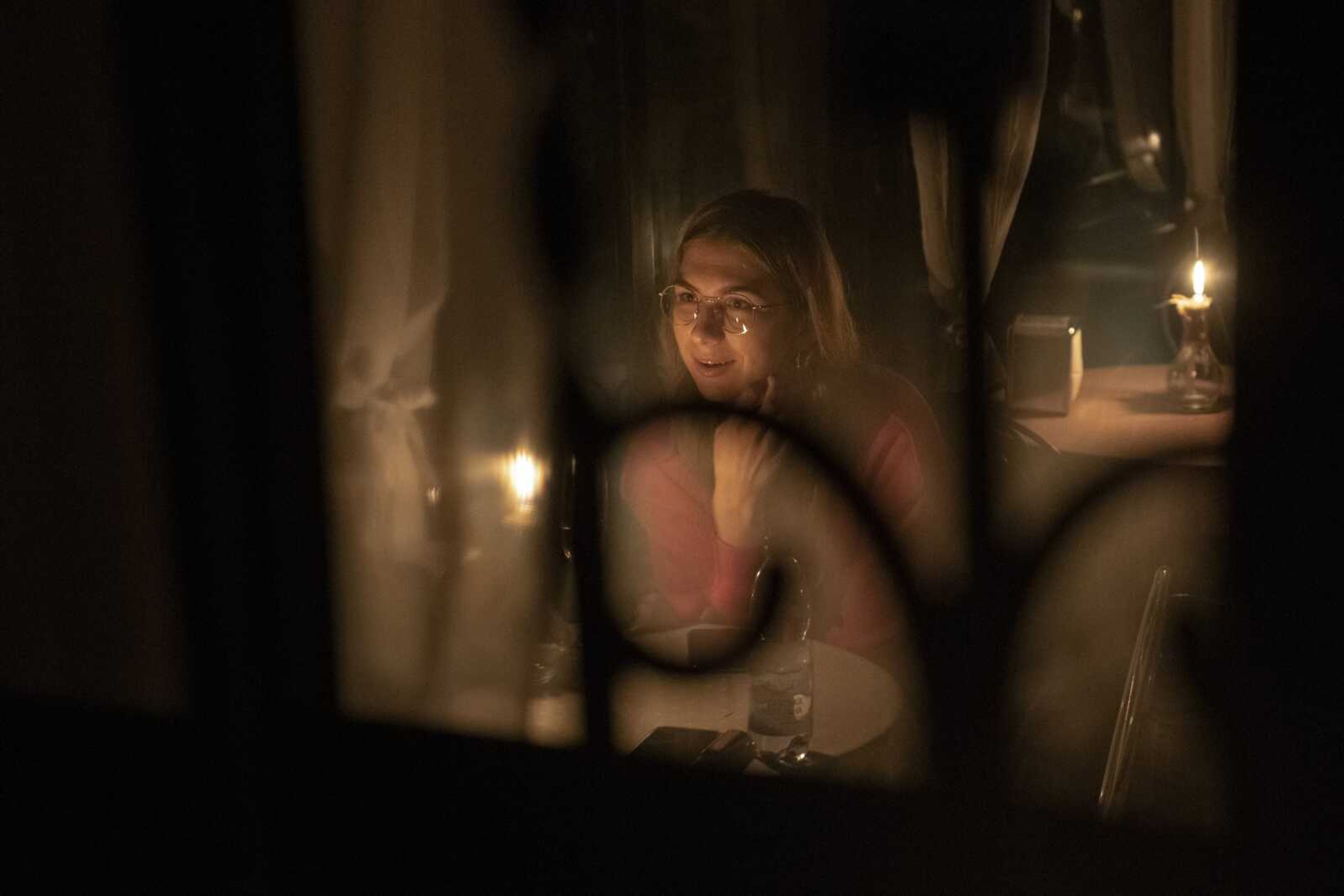 A woman sits in a cafe during a blackout Friday, Nov. 4, in Kyiv, Ukraine.