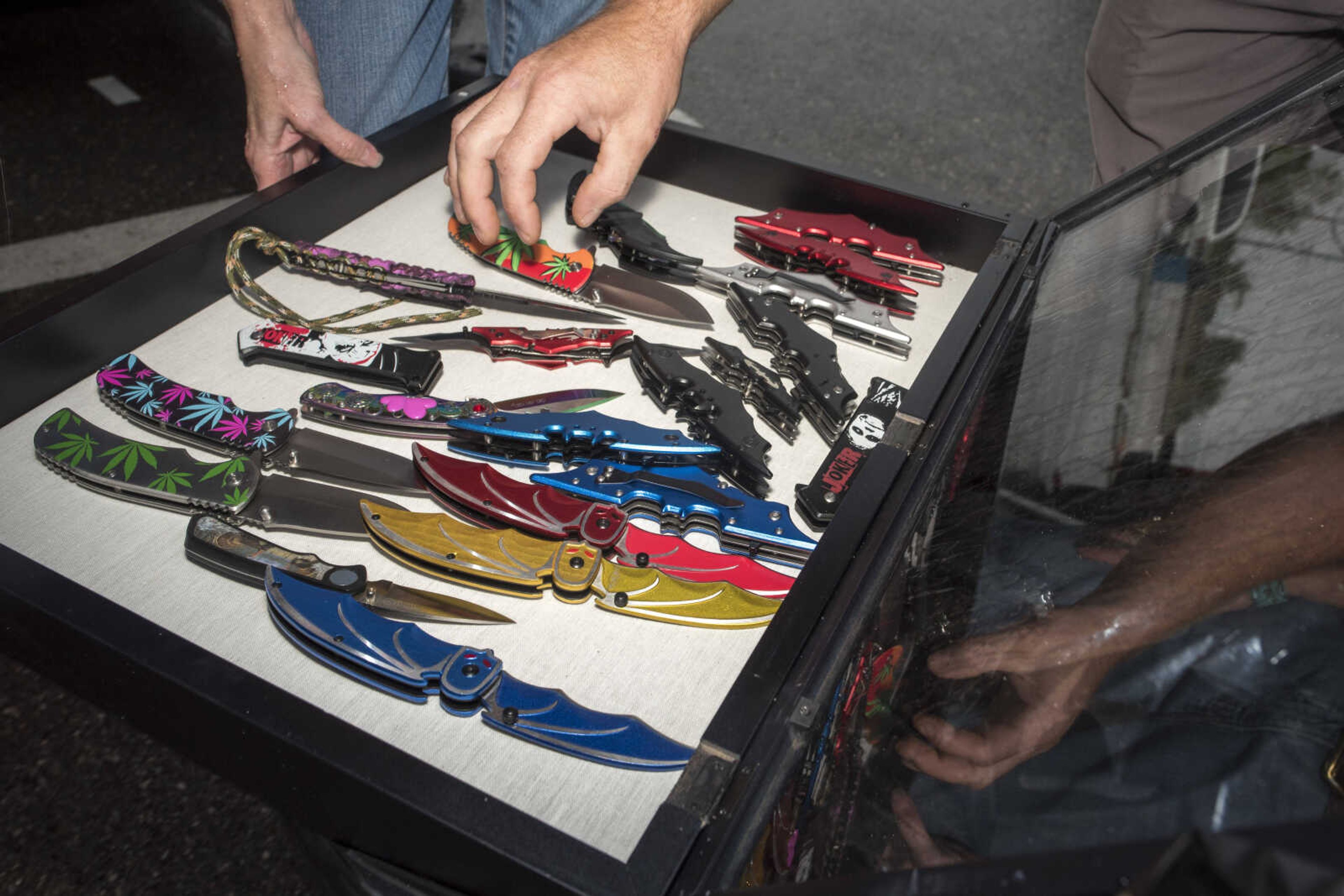 Poplar Bluff vendor Jennifer House holds a display of knives for her final customer of the day, Cape Girardeau resident Nate Malone, right, to view Sunday, Oct. 6, 2019, at the Cape Girardeau Downtown Tailgate Flea Market.