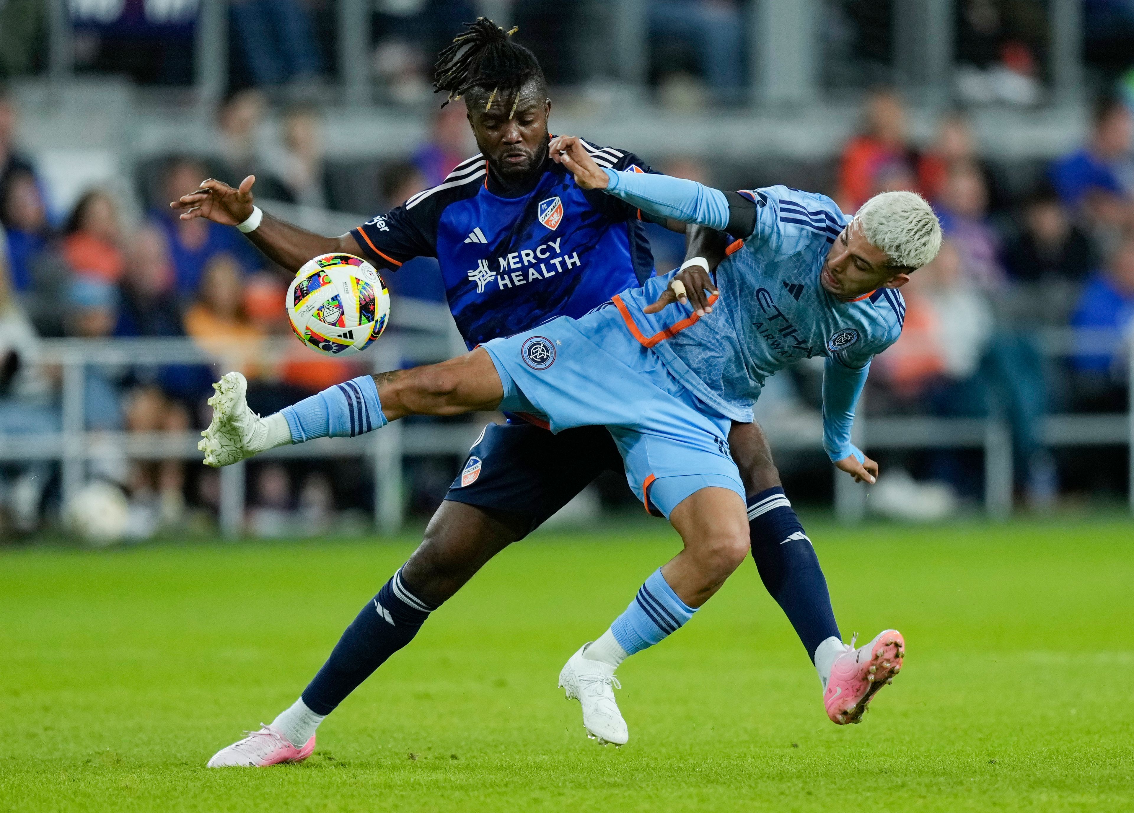 FC Cincinnati defender Chidozie Awaziem, left, and New York City FC midfielder Santiago Rodríguez, right, fight for the ball during the first half of a first-round soccer match of the MLS Cup playoffs, Monday, Oct. 28, 2024, in Cincinnati. (AP Photo/Carolyn Kaster)