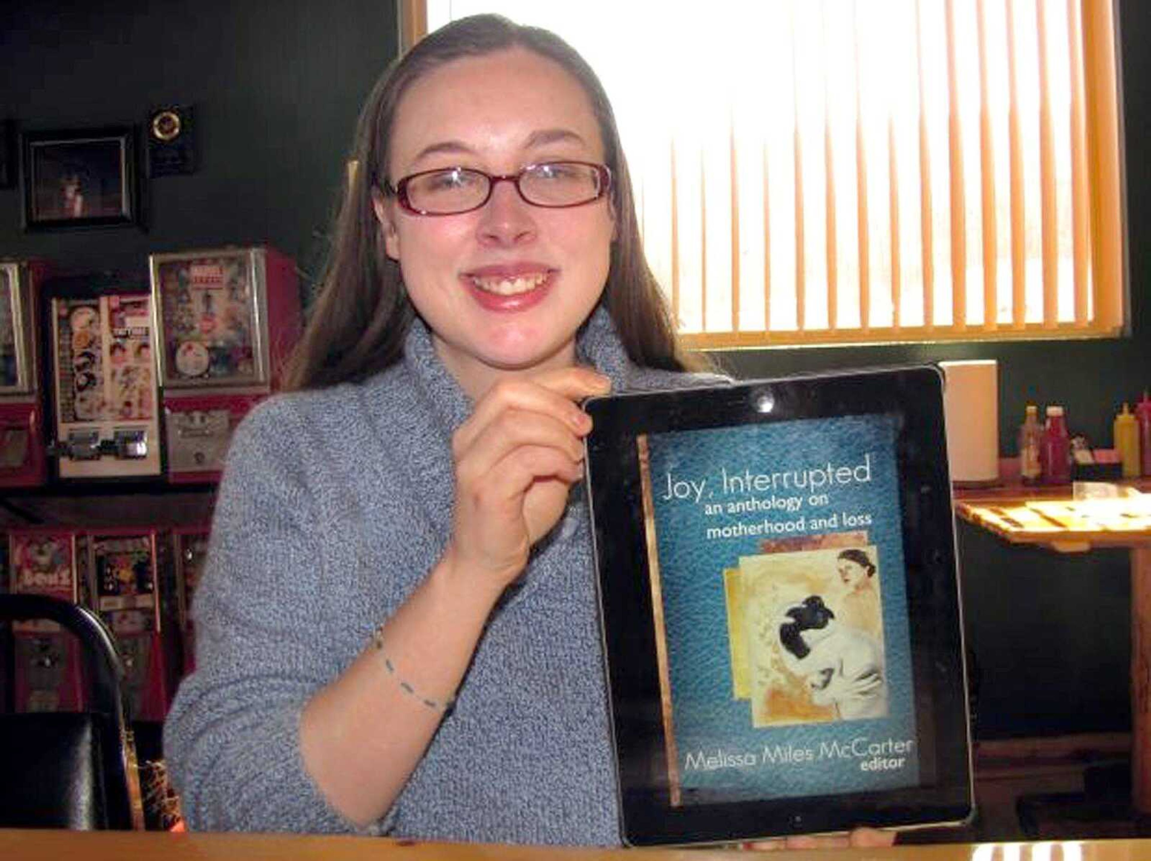 Melissa Miles McCarter poses with the Kindle version of her book &#8220;Joy Interrupted&#8221; on her iPad. (Submitted)