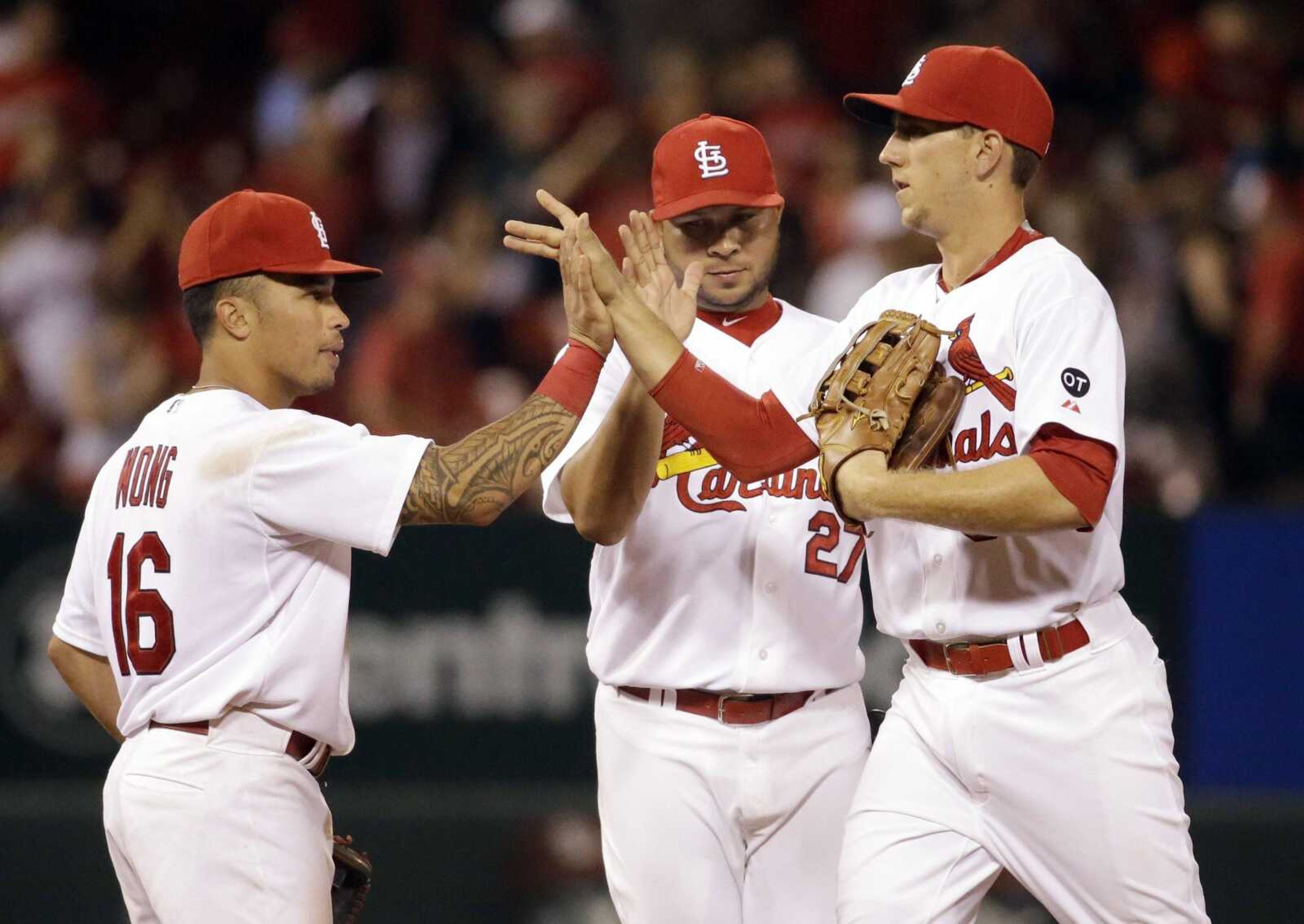 St. Louis Cardinals, from left to right, Kolten Wong, Jhonny Peralta and Stephen Piscotty celebrate following the Cardinals' 2-1 victory over the San Francisco Giants in a baseball game Monday, Aug. 17, 2015, in St. Louis. (AP Photo/Jeff Roberson)