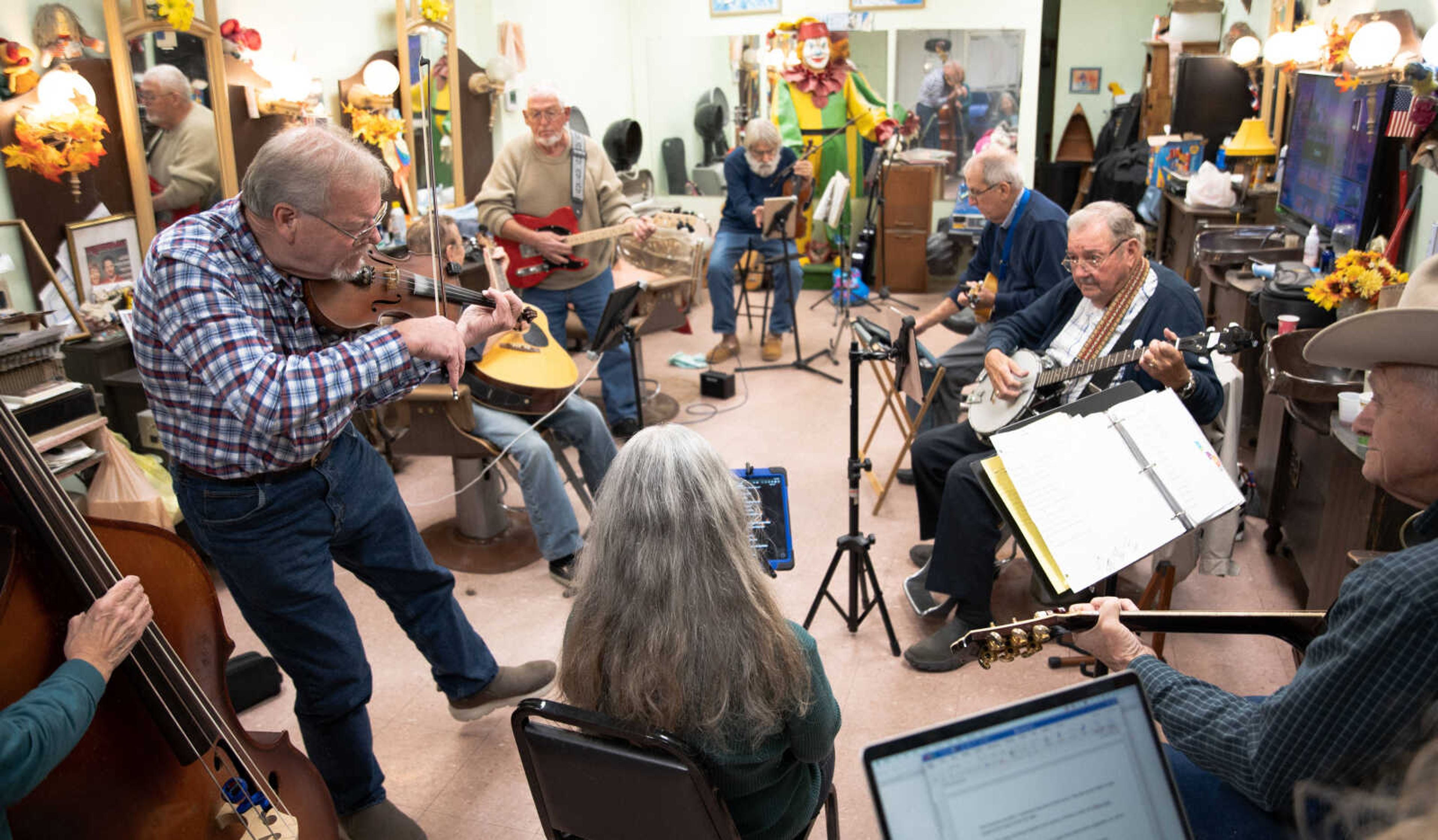 John Simmons plays a solo at the weekly jam session at Hombre Barber Shop in Cape Girardeau. In the circle, left to right, are Chris Simmons on bass, John Simmons on violin, Gene Penny on acoustic guitar, Paul Brown on electric guitar, Jim New on violin, Bo Tollison on ukulele and harmonica, Dean Percival on banjo, Jim Shandy on guitar and Cecilia Mungle on vocals.