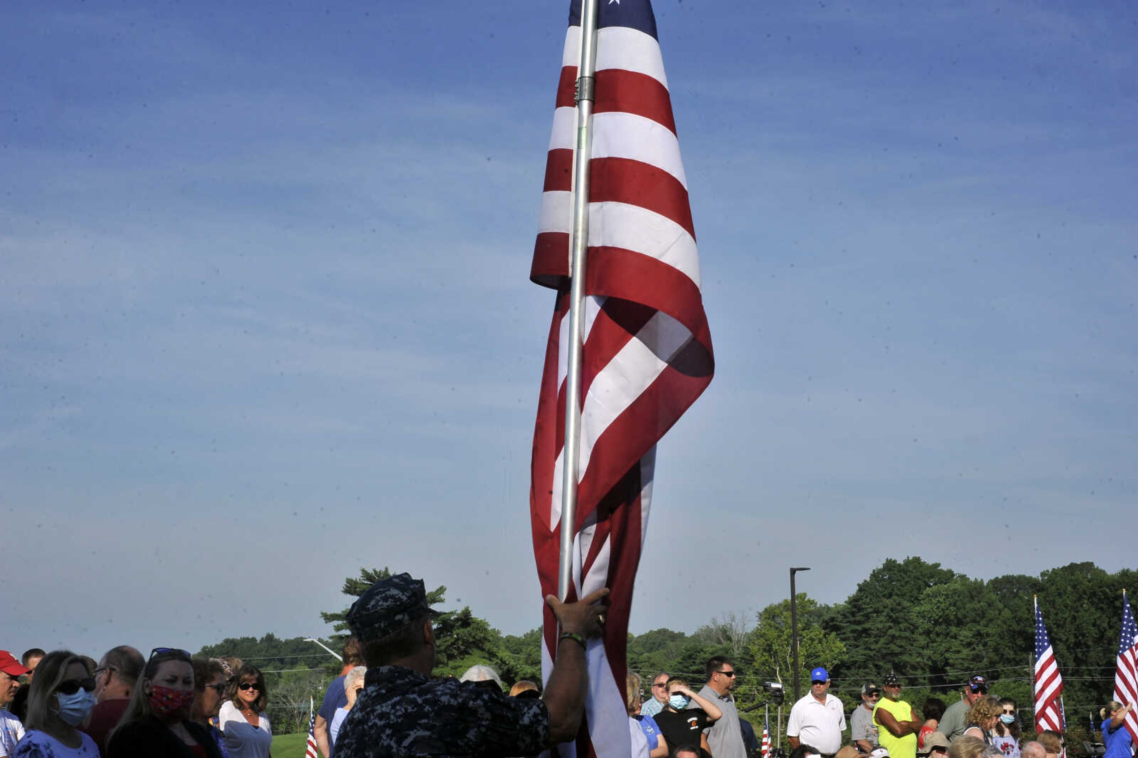 Navy veteran David Cantrell lifts a flag before it is dedicated to a veteran during the Avenue of Flags ceremony.&nbsp;