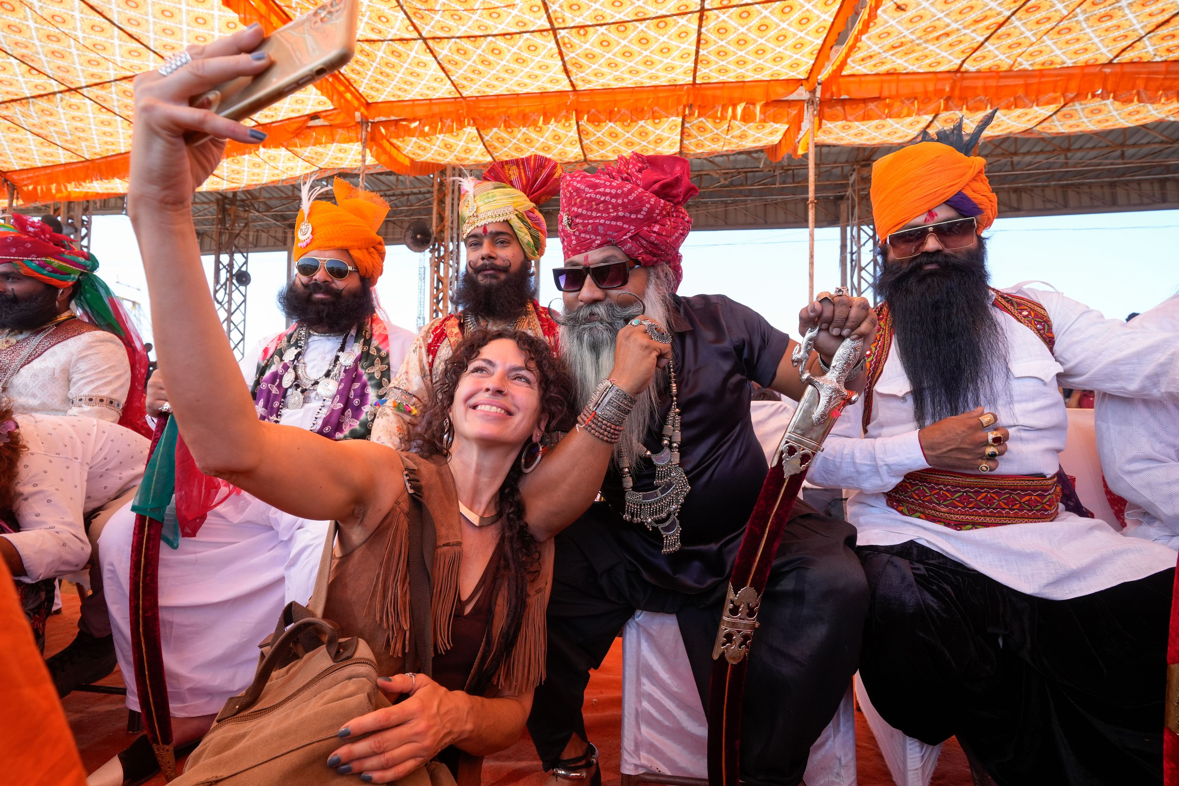 A tourist takes a selfie with a group of men participating in a moustache competition during a camel fair in Pushkar, in the northwestern Indian state of Rajasthan, Wednesday, Nov. 13, 2024. (AP Photo/Deepak Sharma)