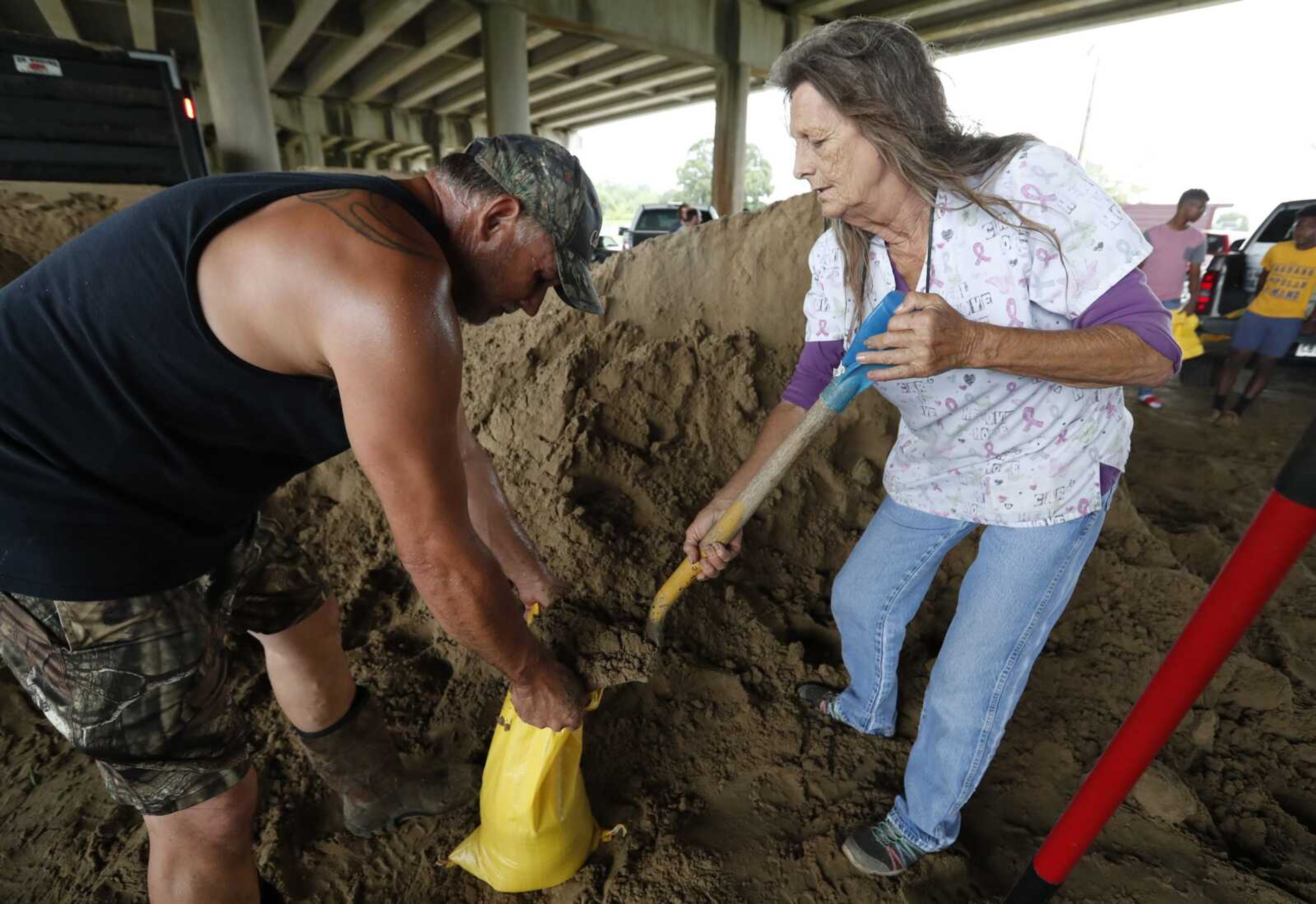 Judy Daigle, owner of "The Chili House and More," right, helps Michael Fuselier fill a sandbag Friday at one of several locations in Morgan City, Louisiana.