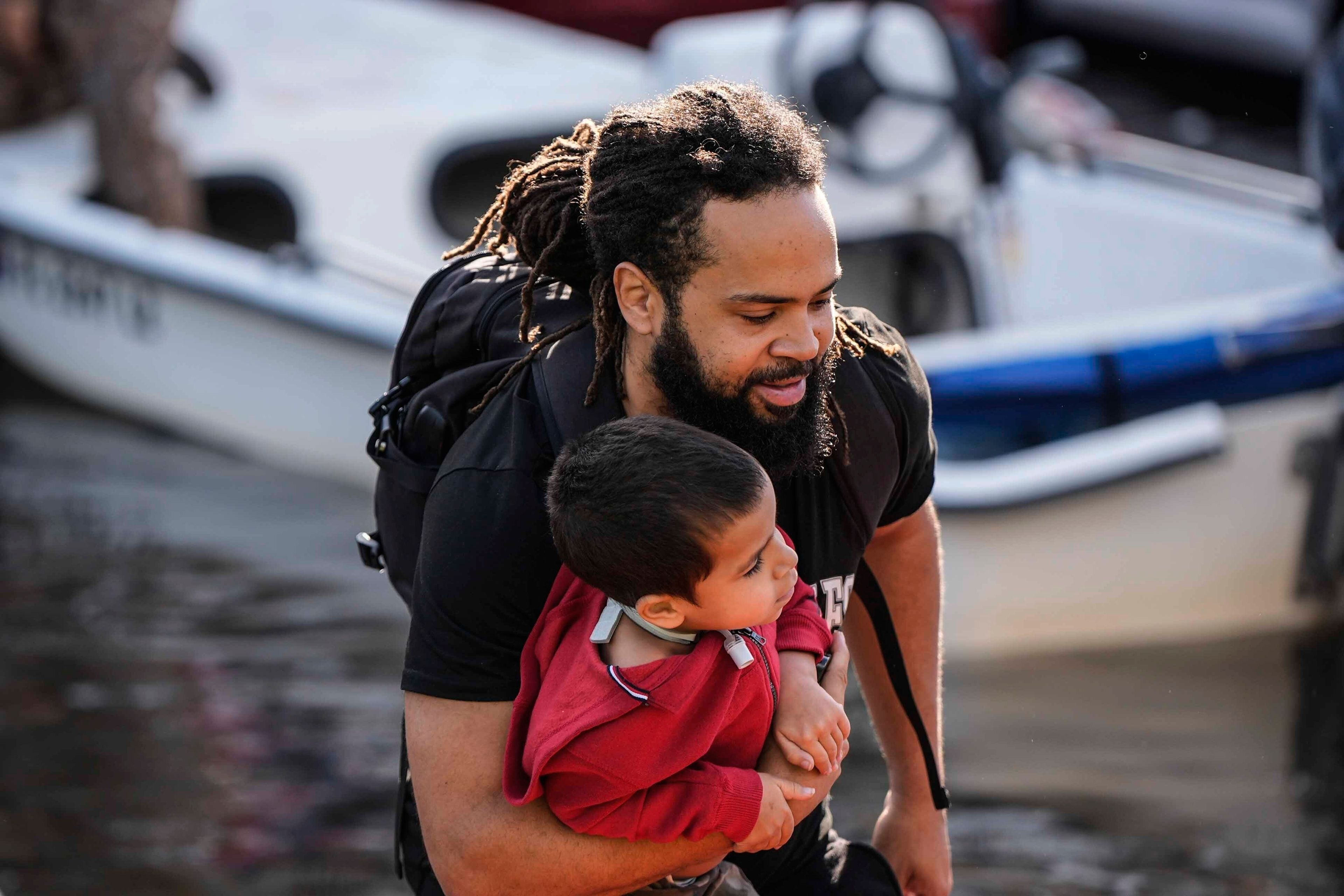 A man and child leave a rescue boat after high floodwaters entered their apartment in the aftermath of Hurricane Milton, Thursday, Oct. 10, 2024, in Clearwater, Fla. (AP Photo/Mike Stewart)