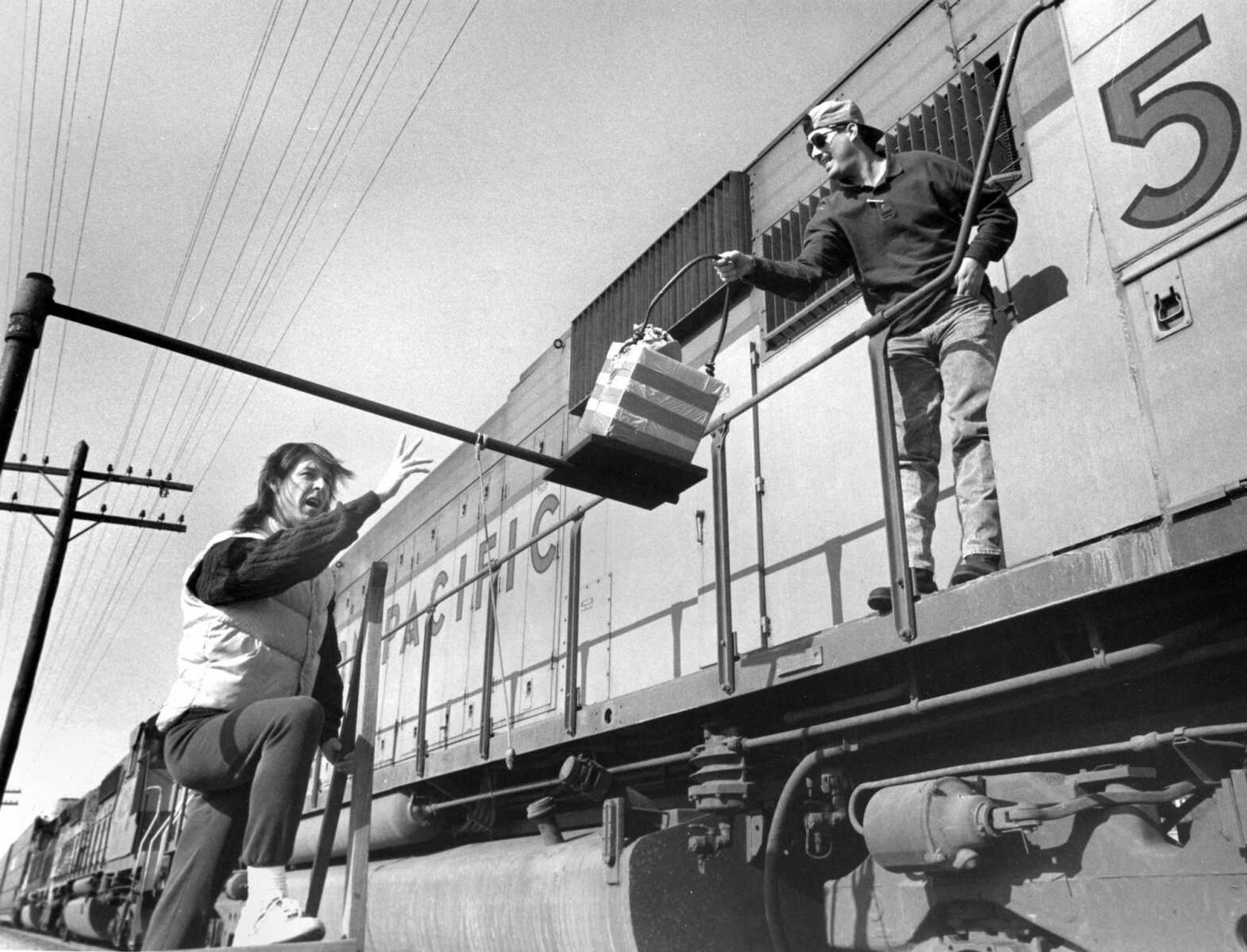 Bob Camp Jr., left, puts a lunch order "on the hook" for conductor Steve Augustine aboard a Union Pacific freight train traveling through Scott City, Missouri. Camp operates The Beanery that serves 30 trains a day on the run. Feb. 16, 1993. (Fred Lynch)