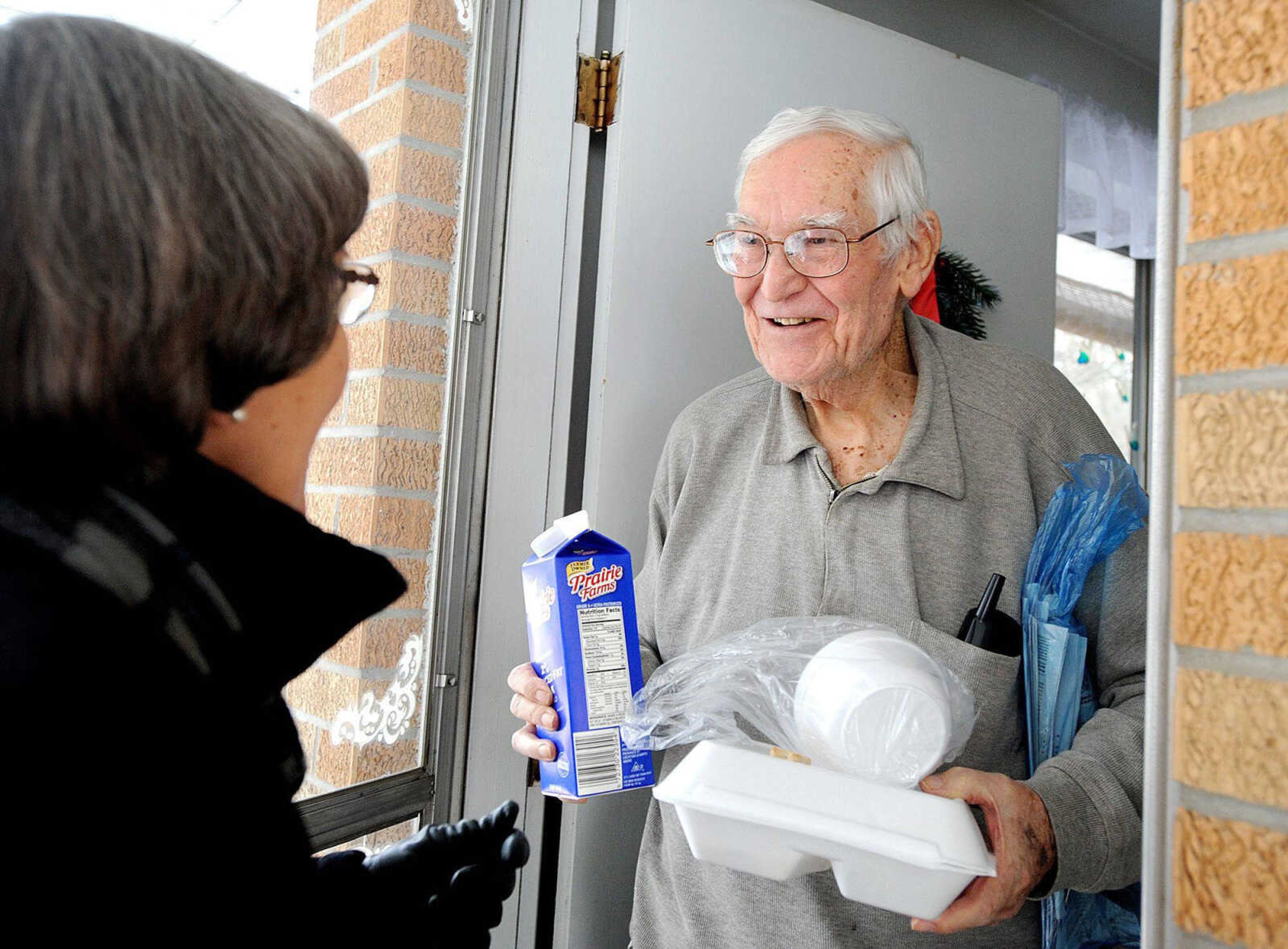 Harry Ivester chats with June Readnour as she delivers an armful of food, a carton of milk and a dog treat for his four-legged friend to his Cape Girardeau home. (Laura Simon)