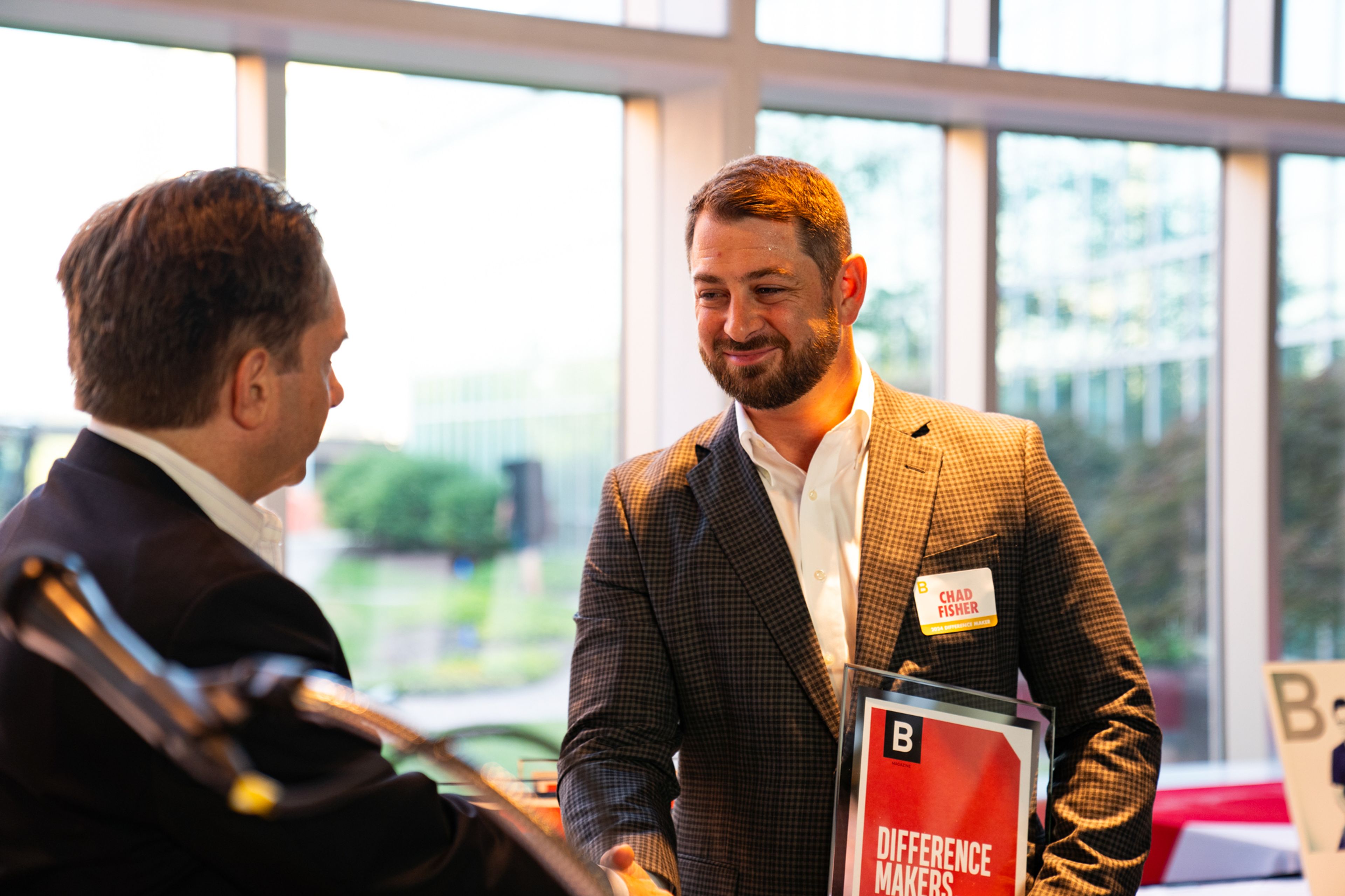 Chad Fisher shakes hands with Southeast Missourian publisher Jon Rust after he received recognition as a 2024 Difference Maker.