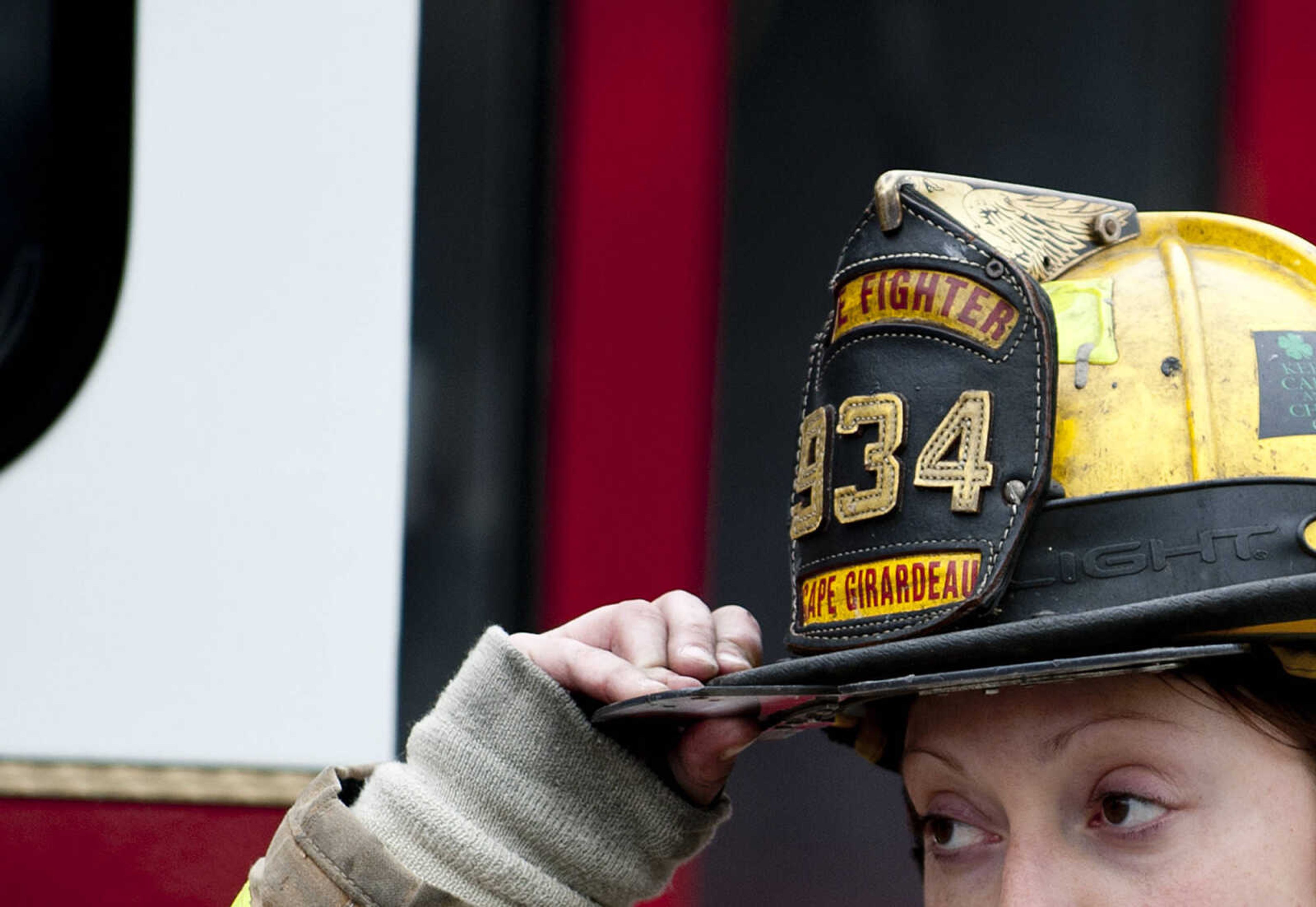 A firefighter adjusts her helmet as the Cape Girardeau battle battle a structure fire at 710 Morgan Oak St., Tuesday, April 29, in Cape Girardeau. A Cape Girardeau Police officer saw the fire and called it in at 1:16 p.m. The building contained two apartments that were home to five people, though no one was home at the time of the fire. The cause of the fire is under investigation.