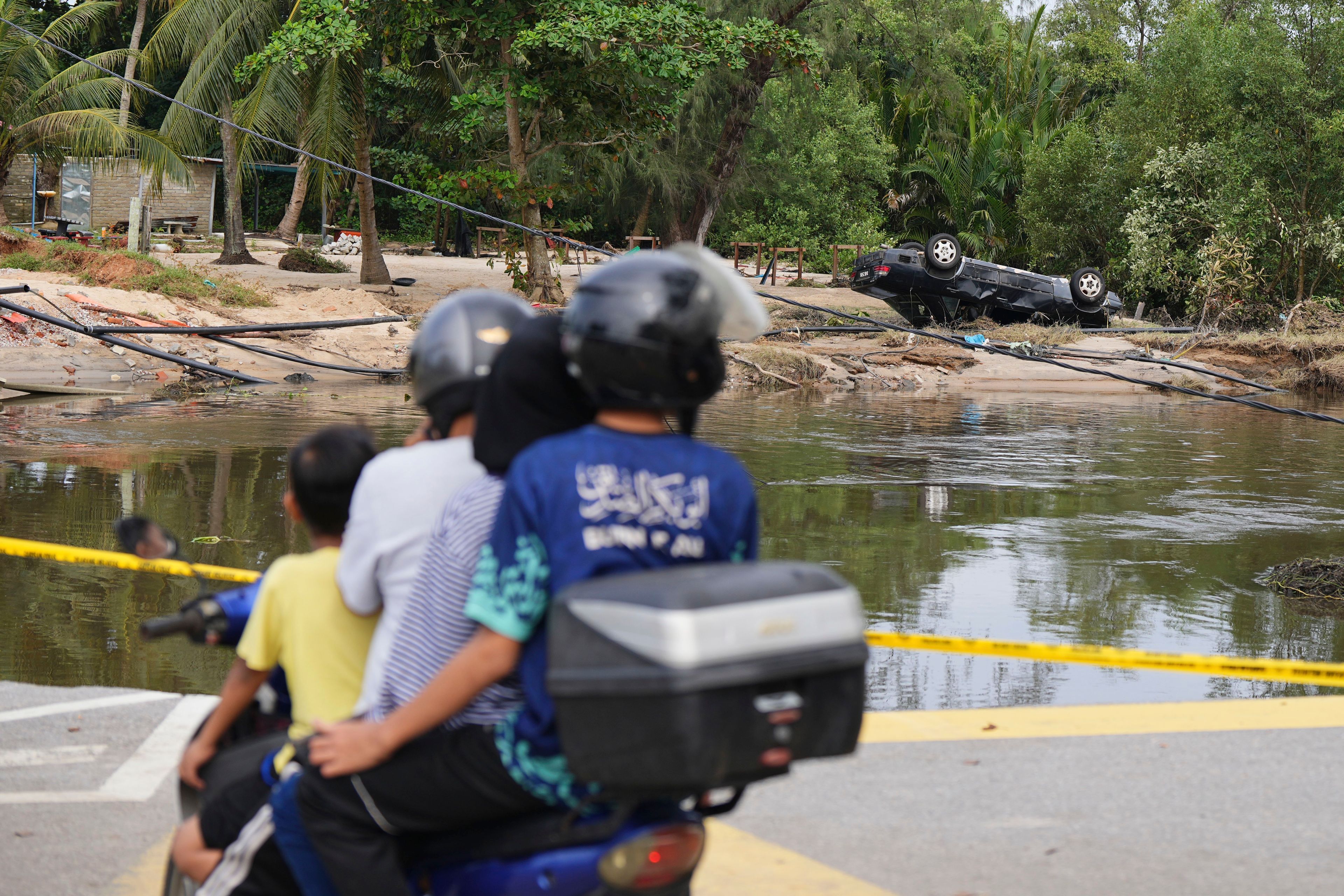 Motorists survey the damage caused by a flood in Tumpat, on the outskirts of Kota Bahru in Kelantan state on the east coast of Malaysia, Tuesday, Dec. 3, 2024. (AP Photo/Vincent Thian)