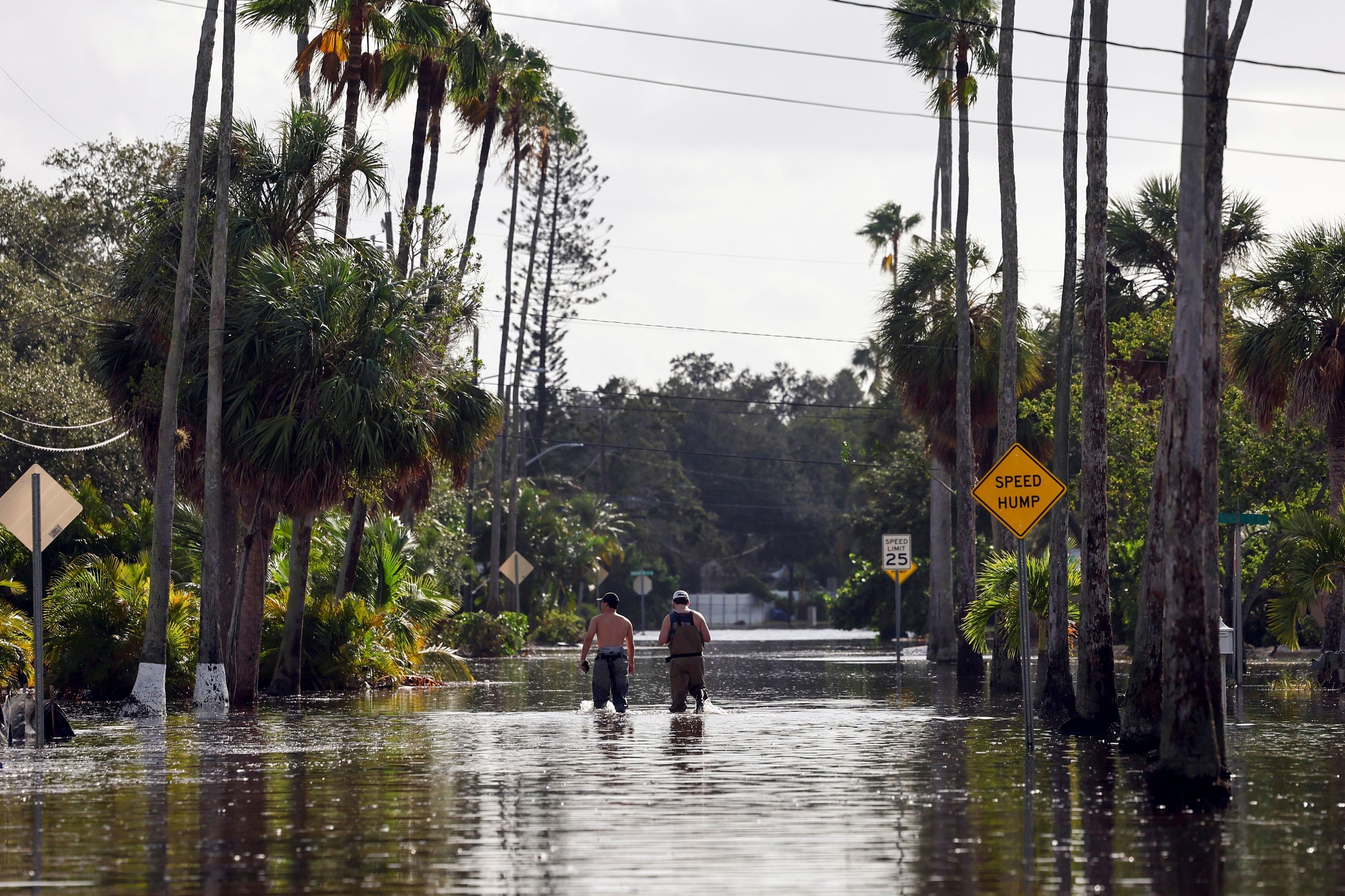 FILE - Men walk down a street flooded by Hurricane Helene in the Shore Acres neighborhood Sept. 27, 2024, in St. Petersburg, Fla. (AP Photo/Mike Carlson, File)