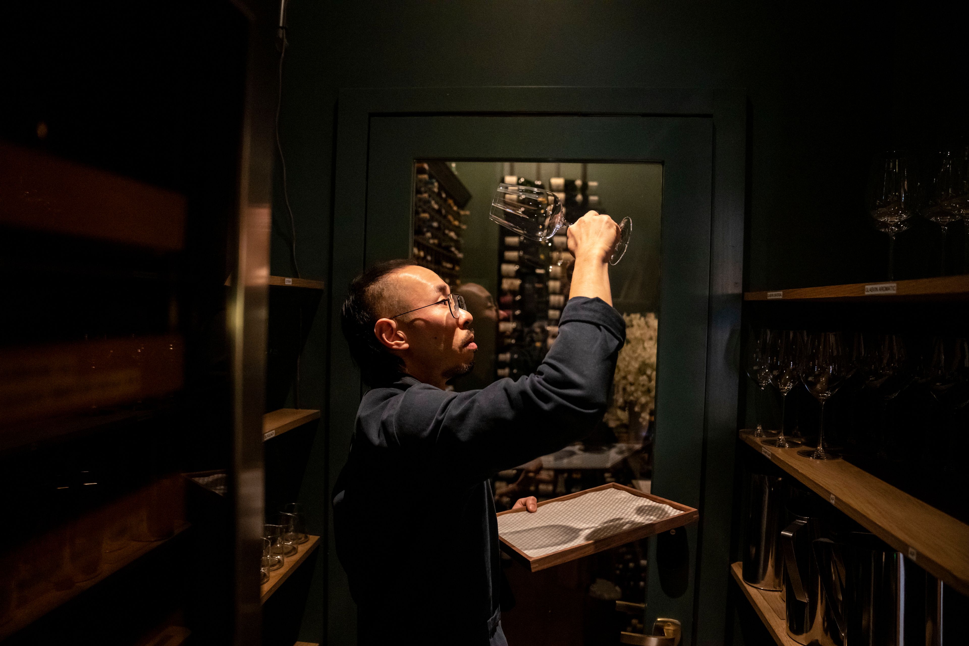 Robert Calabretta inspects wine glasses at the restaurant where he works, Thursday, Feb. 15, 2024, in New York. (AP Photo/David Goldman)