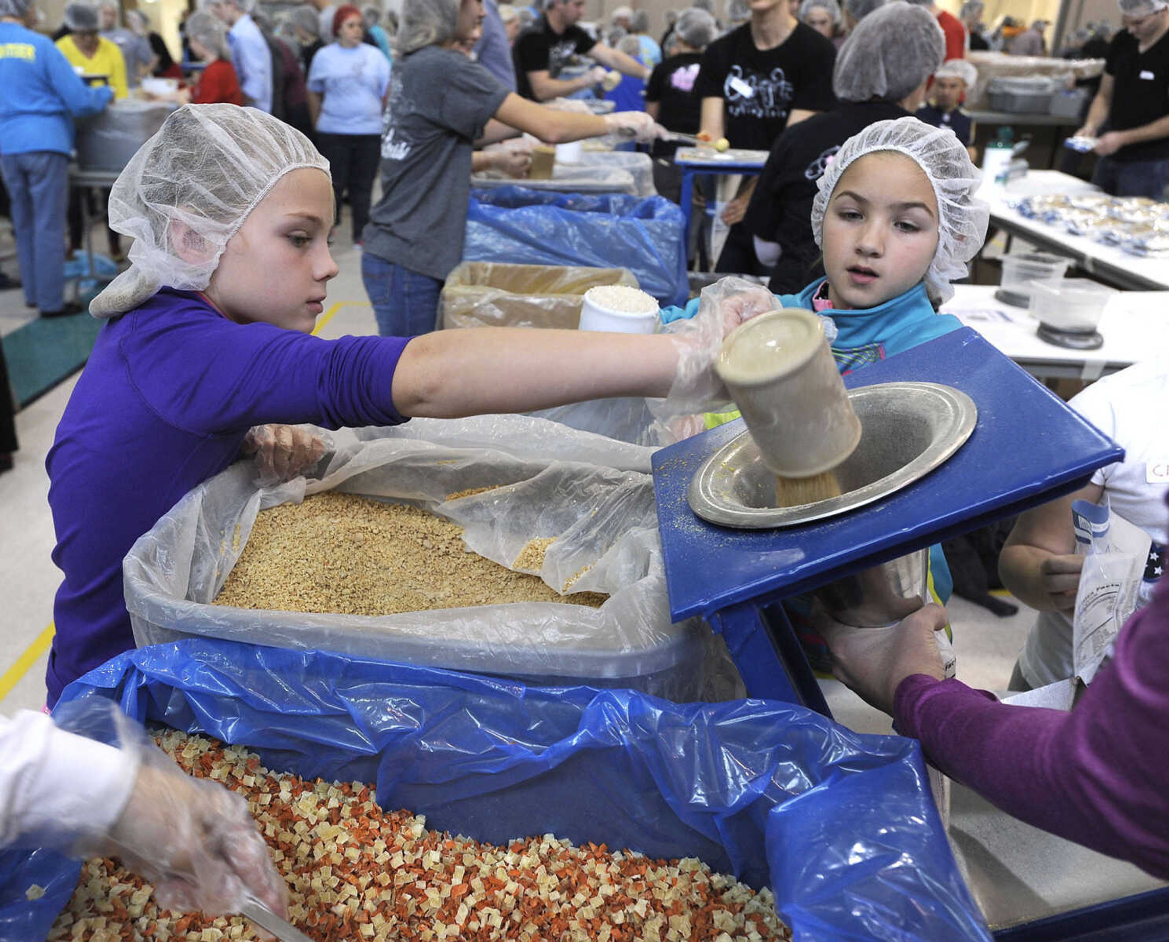 FRED LYNCH ~ flynch@semissourian.com
Emerson Pitts, left, pours soy as Ella Clifton waits to add rice on the MannaPack line at the Feed My Starving Children MobilePack event Sunday, Dec. 7, 2014 at the Osage Centre in Cape Girardeau. More than 3,100 volunteers were expected to fill 800,000 bags with food over the 3-day event hosted by LaCroix Church.