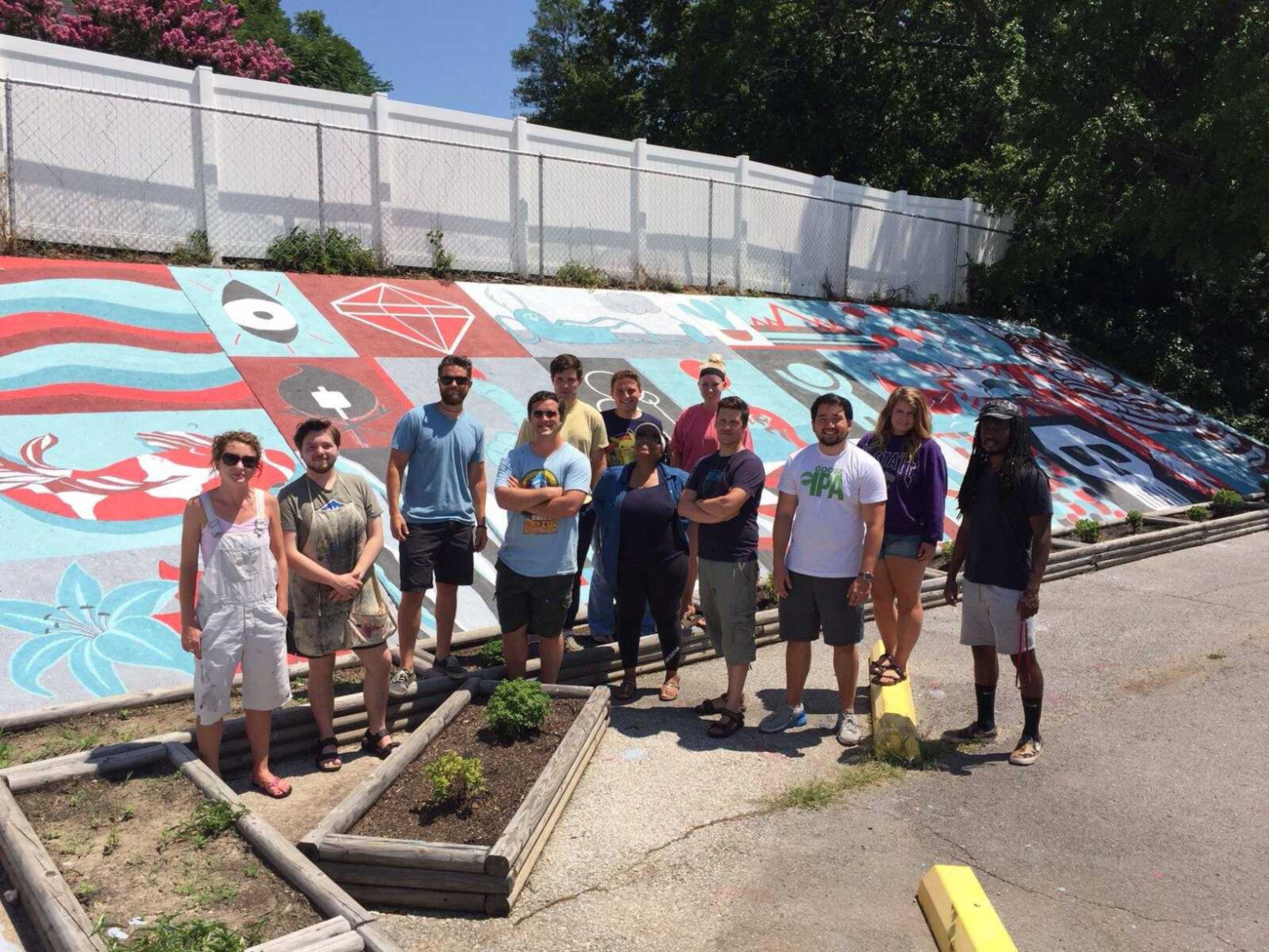 Southeast Missouri State University art students, from left, Sara Hoefer, Logan Blankenship, associate professor and exhibitions coordinator Justin Henry Miller, student Nick Jakubeck, Terry Davis, Brendan McGraw , Alyscia Travis, Taylor Holthaus , Michael Copeland , Scott Stuhldreher, Brooke Kuehny, Haile Wilson (Not pictured: student Jessie Bennett) pose with completed mural at Stevie's Steakburger in Cape Girardeau.