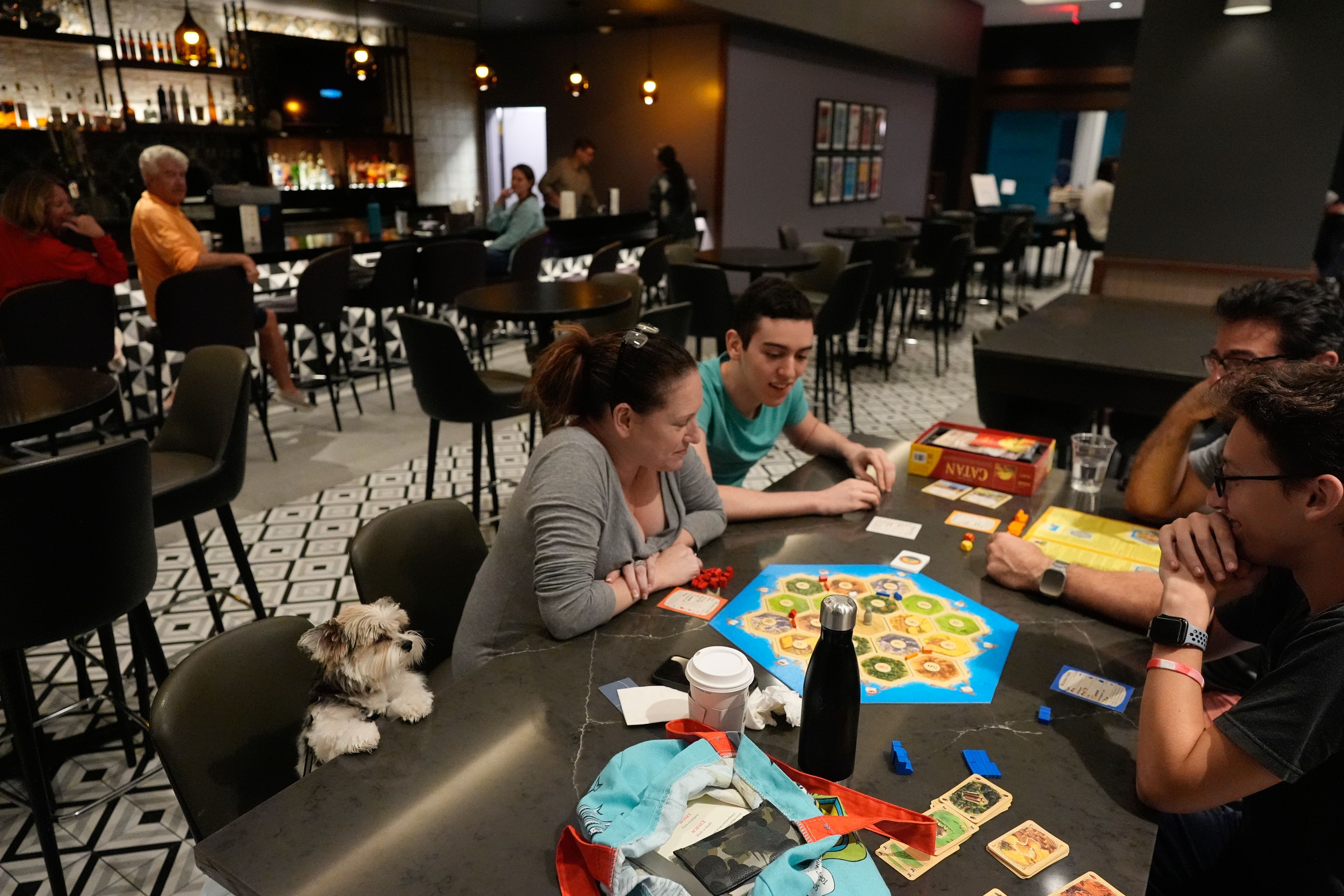 The Segundo family, who evacuated from nearby Davis Island, plays a board game with their dog Cassie looking on, as Hurricane Milton makes landfall on Florida's Gulf Coast, at Hyatt Place Tampa Downtown hotel in Tampa, Fla., Wednesday, Oct. 9, 2024. (AP Photo/Rebecca Blackwell)