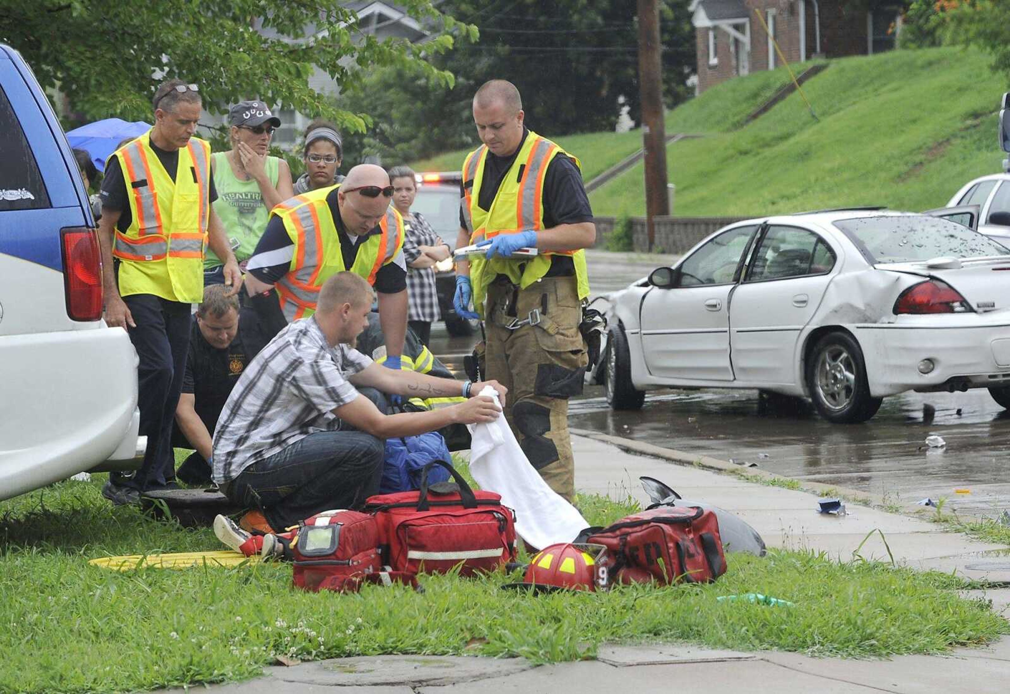 First responders assist a child Friday, June 19, 2015, who was ejected from a Lincoln Navigator that was westbound on Independence Street after it struck a southbound Pontiac Grand Am GT at the Pacific street intersection. Police cited the driver of the Grand Am for failure to yield. (Fred Lynch)