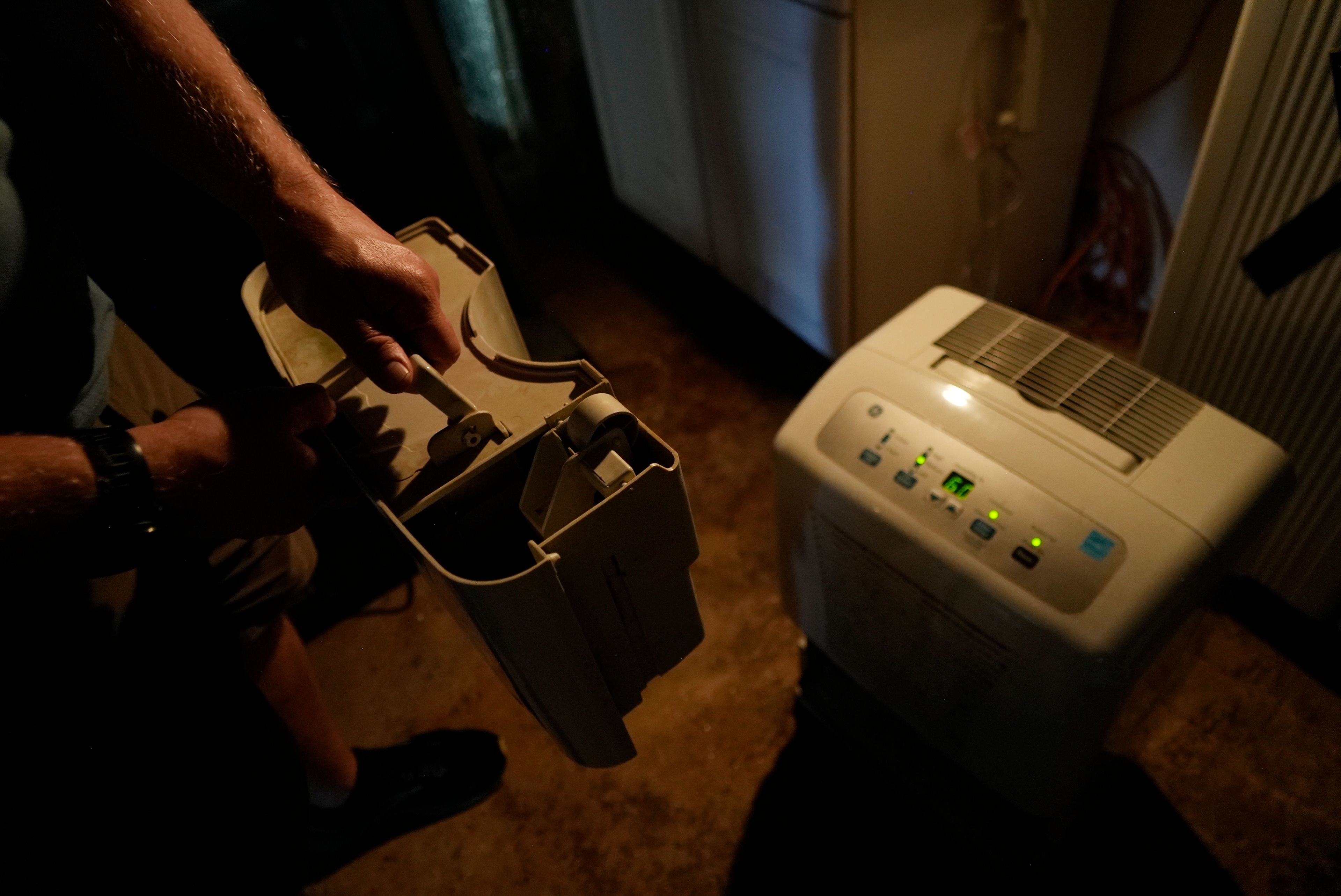 Travis Edwards retrieves water from his basement humidifier to use for flushing toilets Thursday, Oct. 3, 2024 in Asheville, North Carolina. (AP Photo/Brittany Peterson)