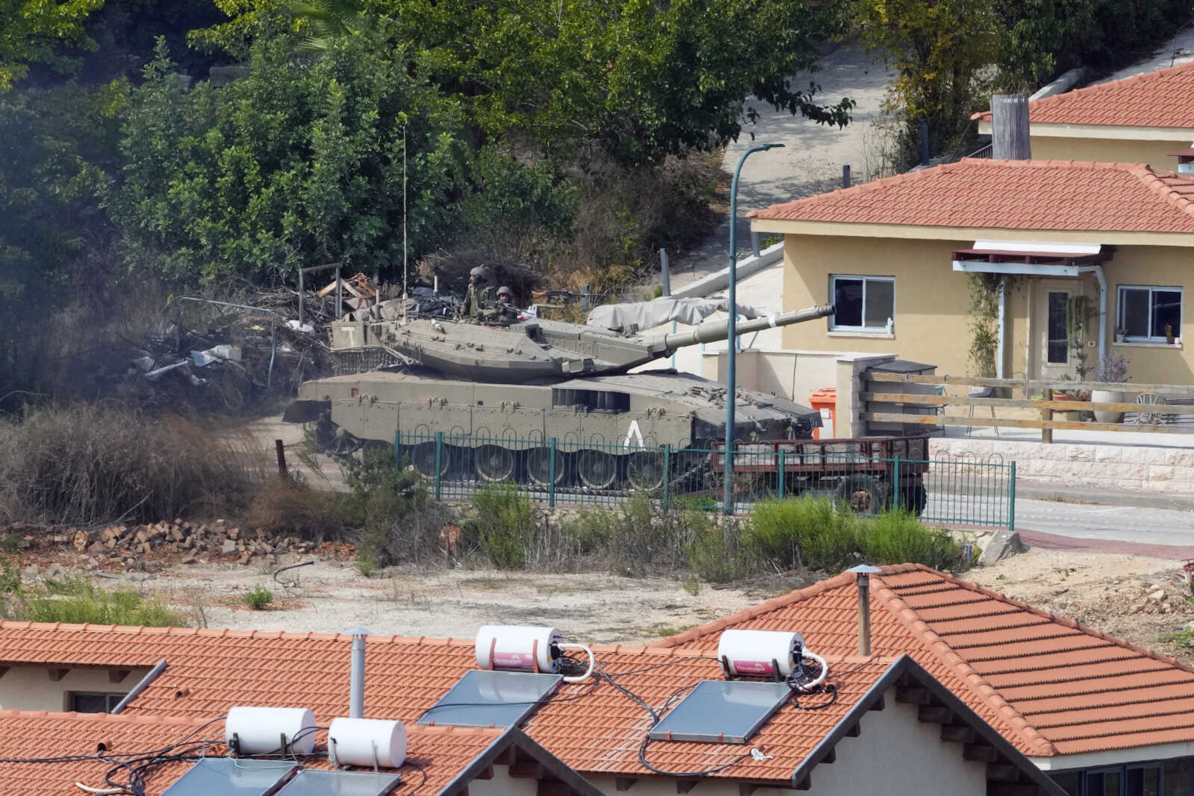 An Israeli tank is deployed between houses in the Israeli town of Metula as seen from the Lebanese side of the Lebanese-Israeli border Monday in the southern village of Kfar Kila, Lebanon.