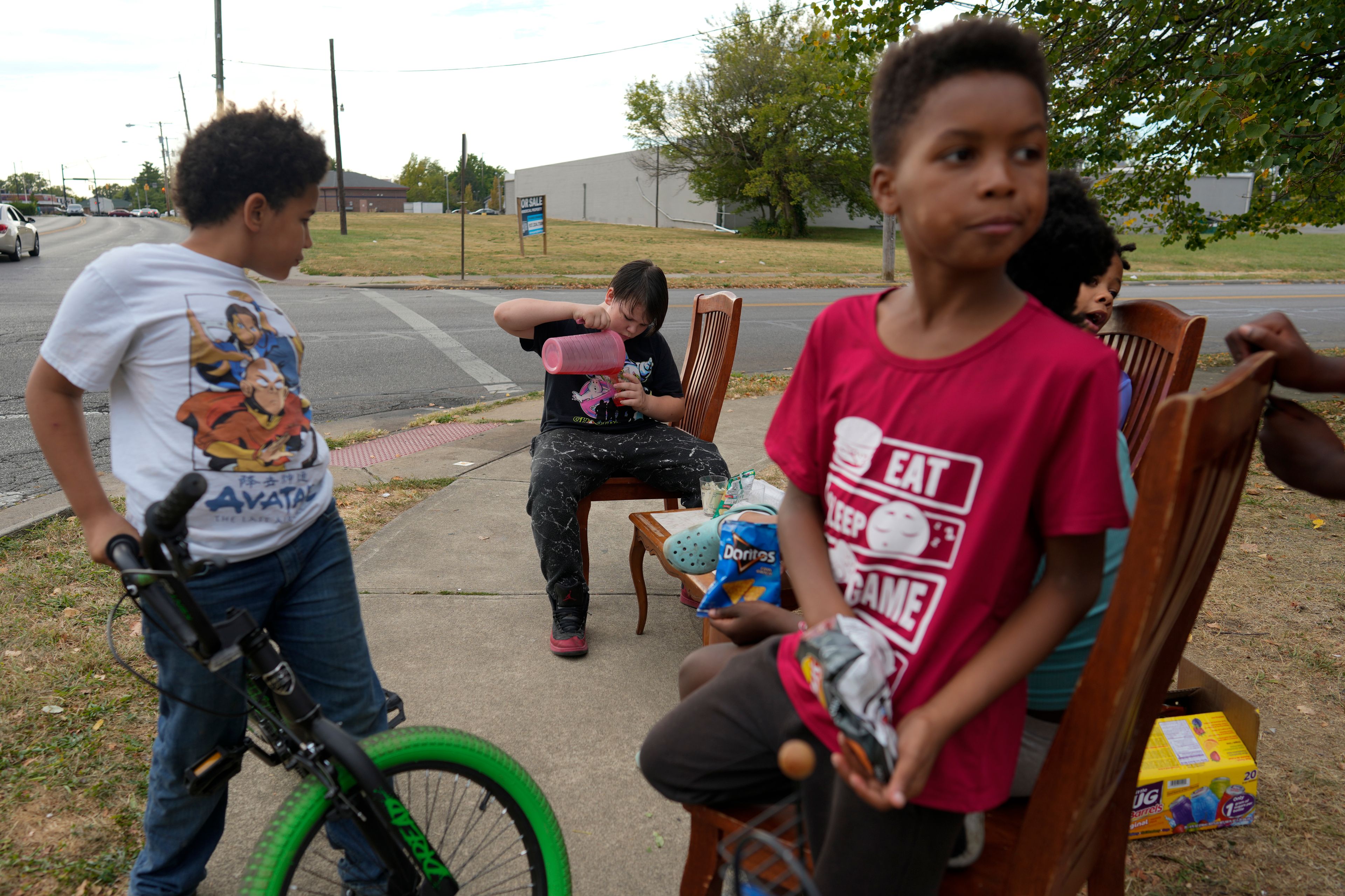 Neighborhood kids gather to sell Kool-Aid and chips, Tuesday, Sept. 17, 2024, in Springfield, Ohio. Some were kept home from school because of the bomb threats at their schools, and if that happens again, they plan to be at the corner with Kool-Aid and chips again tomorrow. (AP Photo/Carolyn Kaster)