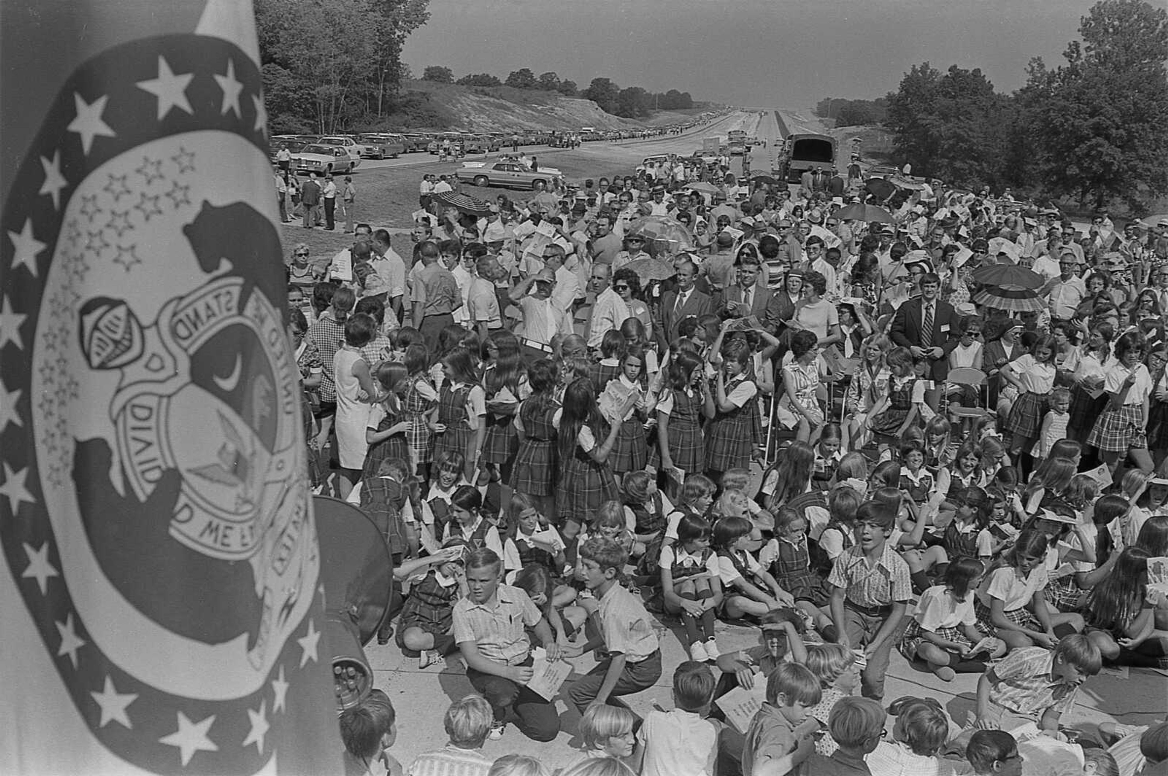 Portion of the estimated 1,500 persons attending the Aug. 30, 1972, Interstate 55 dedication ceremony at Perryville, Missouri, await the arrival of Gov. Warren E. Hearnes and other dignitaries. Photograph was taken from near the speakers' platform. The Missouri Flag is at left in foreground. 