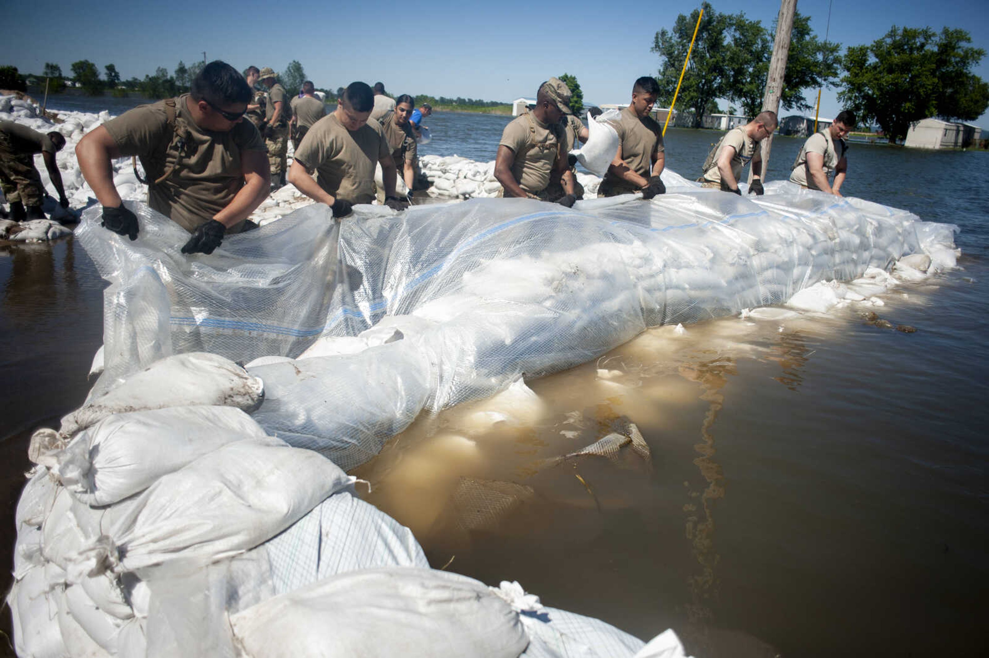 Members of the Illinois National Guard build up existing sandbag barriers to hold back floodwaters Monday, June 10, 2019, along Brookwood Drive in East Cape Girardeau, Illinois.