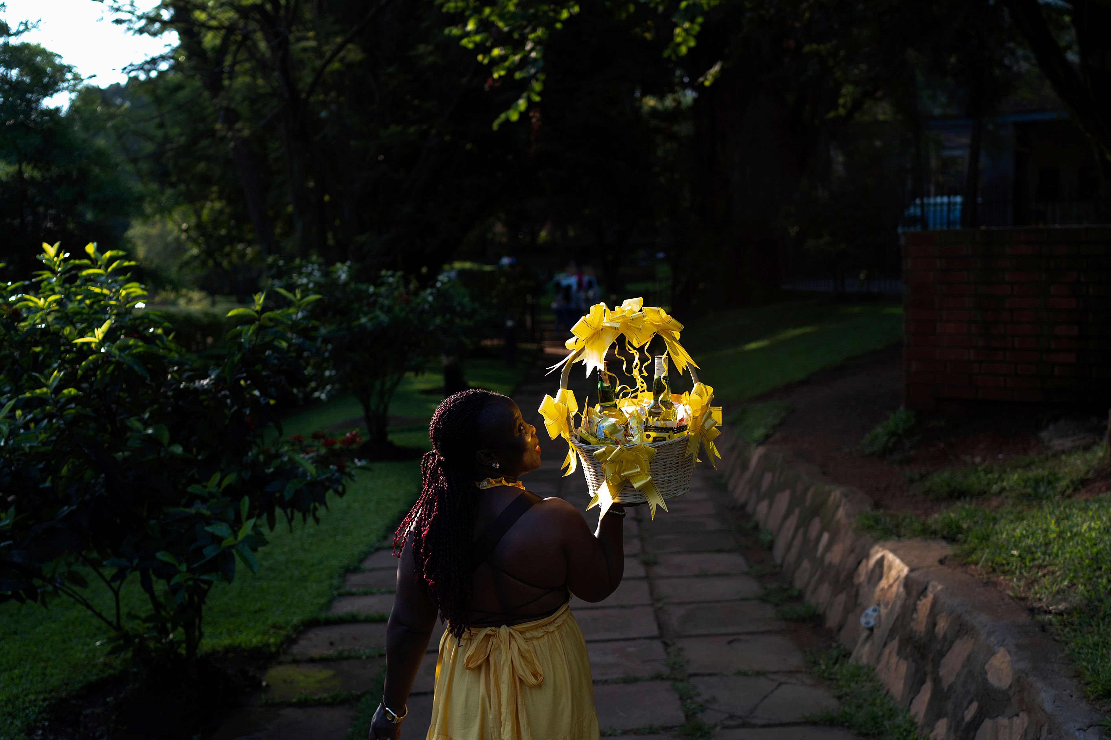 A woman carries a gift basket as she arrives at a park to attend a friend's birthday party, Sunday, Nov. 24, 2024, in Kampala, Uganda. (AP Photo/David Goldman)