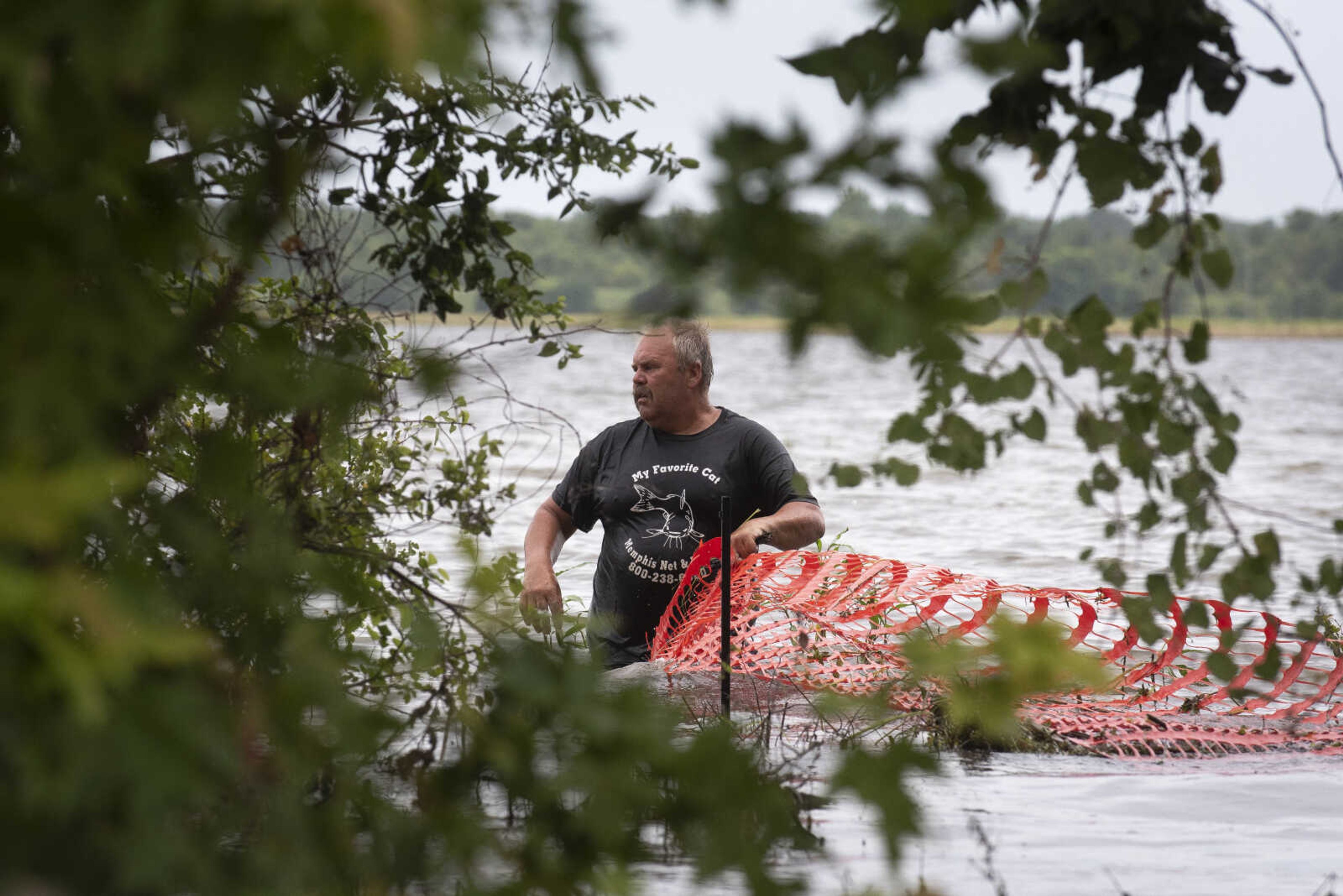 Stacy Gilpin, of Niota, Illinois, wades through floodwaters while helping residents of East Cape Girardeau, Illinois, install barriers to help slow waves on the floodwaters before the waves hit sandbag walls Sunday, July 14, 2019, in East Cape Girardeau, Illinois.