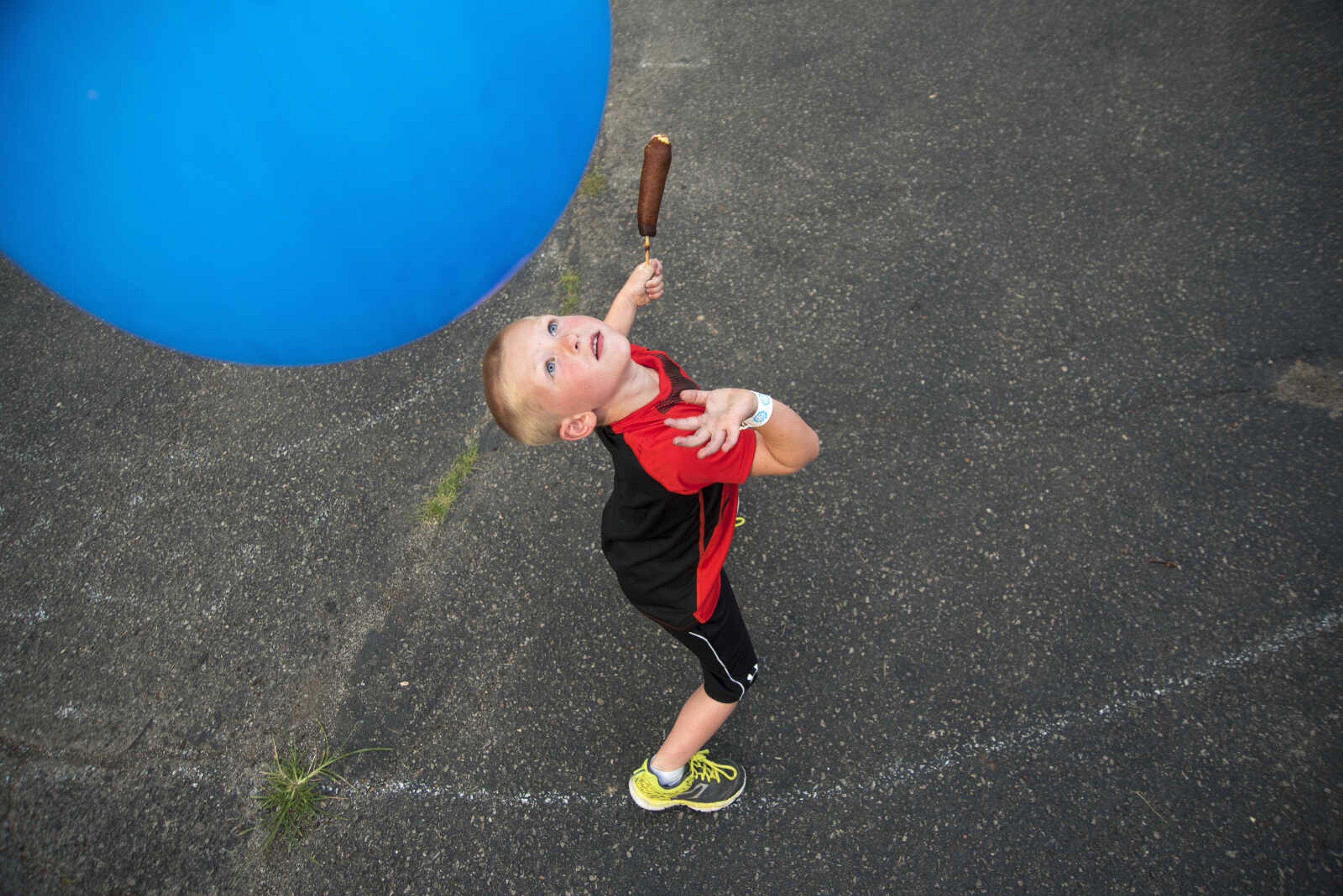 Hunter Thomas, 4, bops his balloon while holding onto his corn dog during the 41st annual Mid-Summer Festival Friday, June 16, 2017 at Scott City Park.