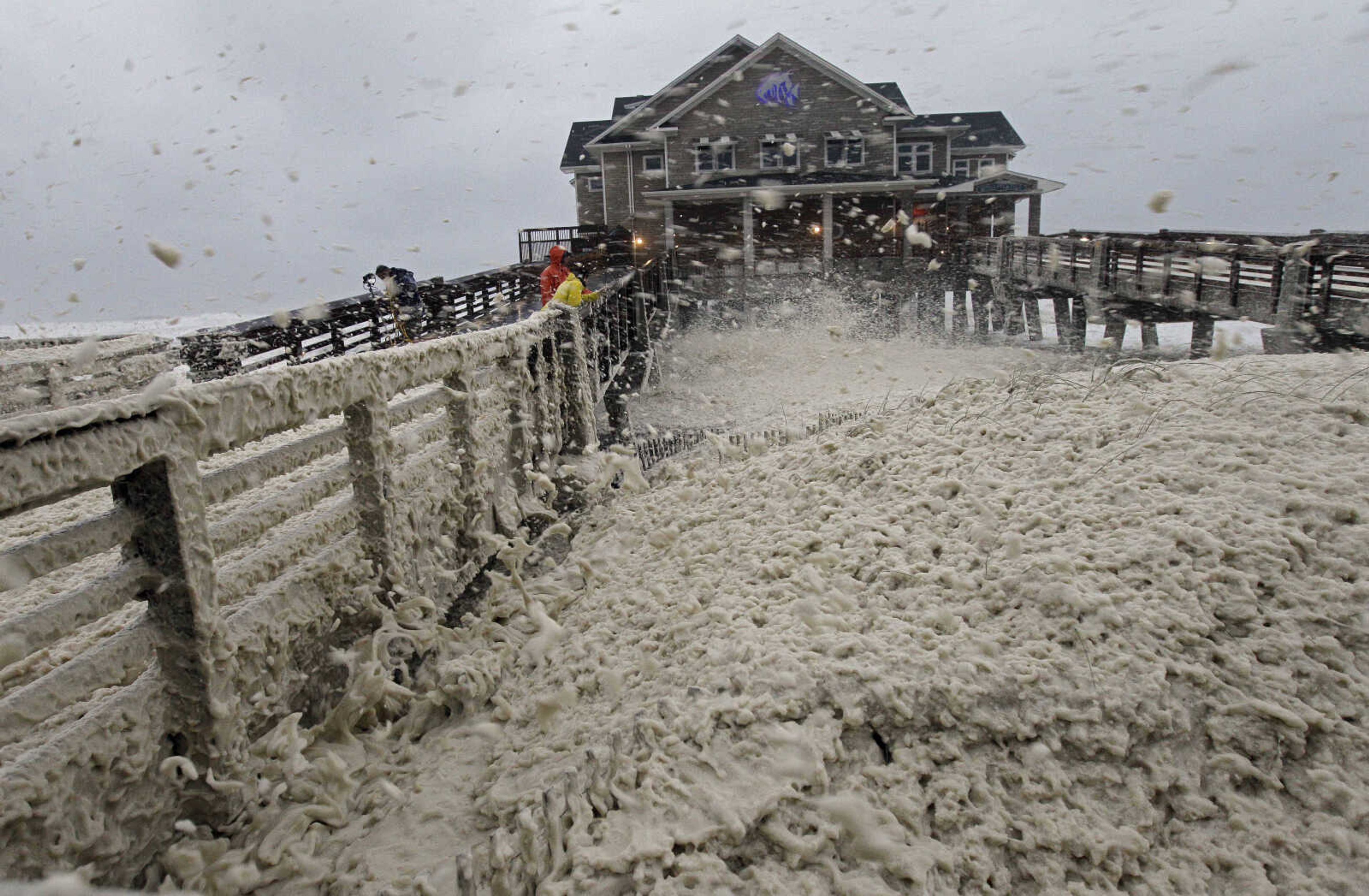 High winds blow sea foam onto Jeanette's Pier in Nags Head, N.C., Sunday, Oct. 28, 2012 as wind and rain from Hurricane Sandy move into the area. Governors from North Carolina, where steady rains were whipped by gusting winds Saturday night, to Connecticut declared states of emergency. Delaware ordered mandatory evacuations for coastal communities by 8 p.m. Sunday. (AP Photo/Gerry Broome)