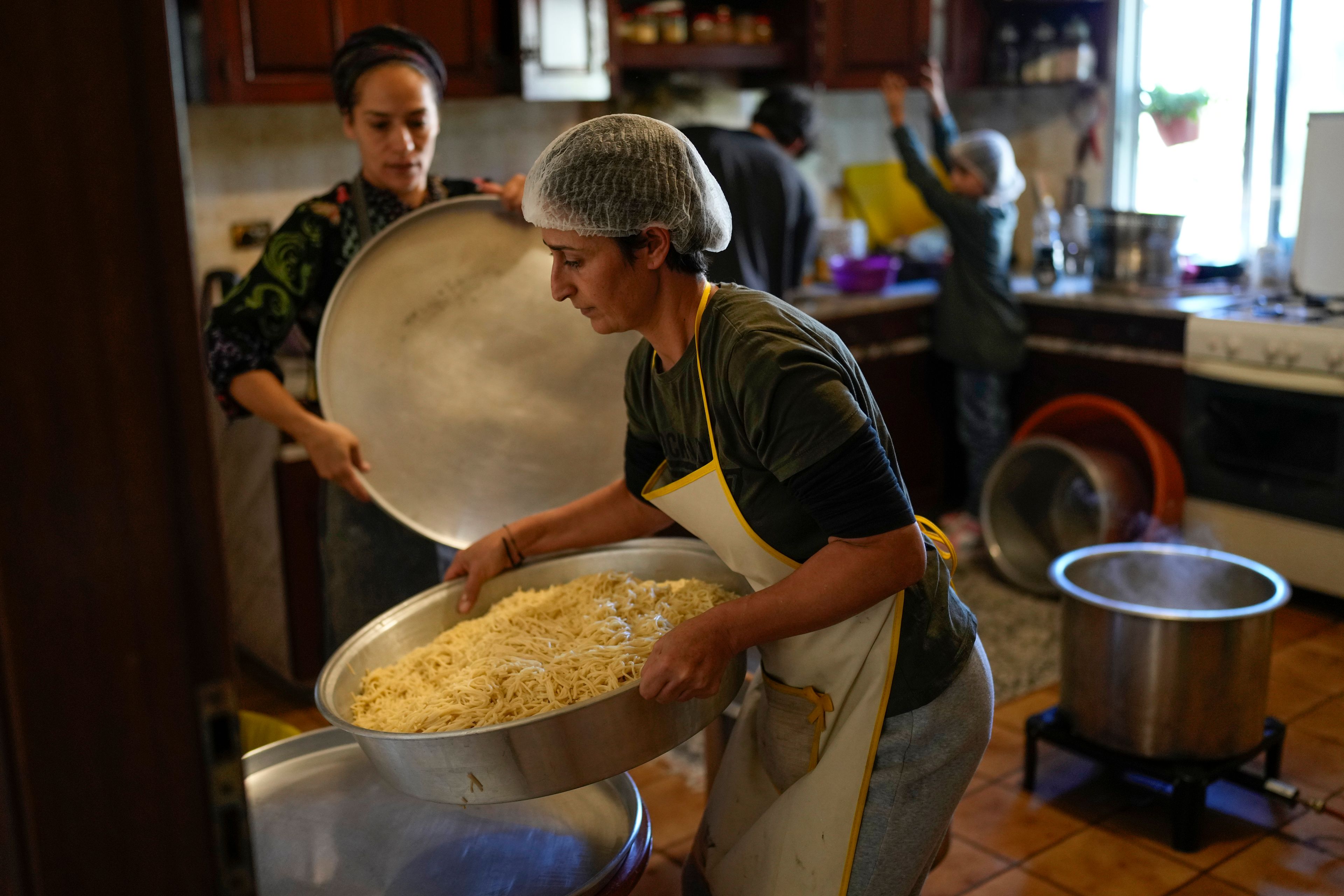 Volunteers prepare meals at a women's art center that was turned into a kitchen for displaced people who fled southern Lebanon amid the ongoing Hezbollah-Israel war, in the town of Aqaibe, northern Lebanon, Thursday, Oct. 24, 2024. (AP Photo/Hassan Ammar)