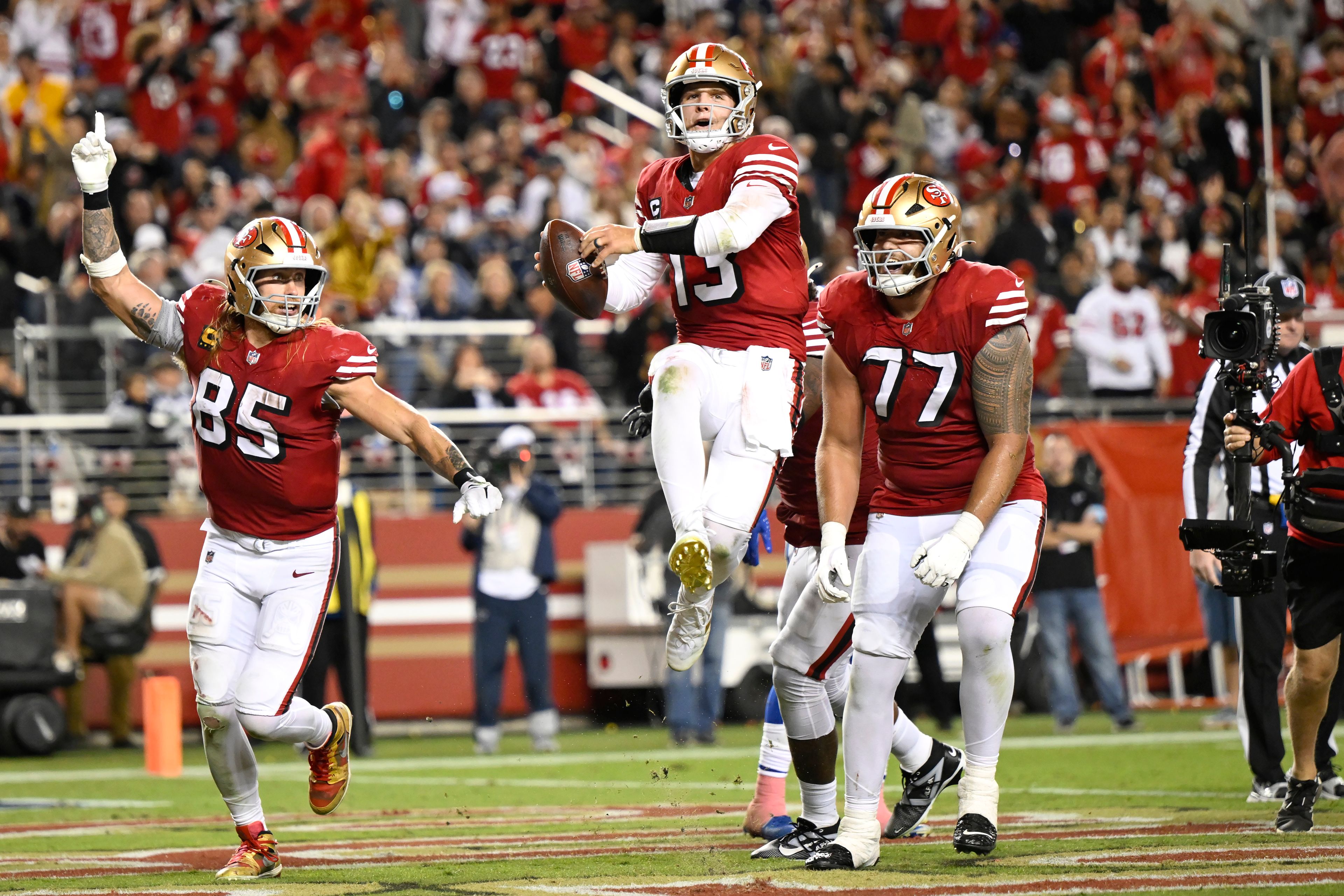 San Francisco 49ers quarterback Brock Purdy, middle, celebrates after scoring a touchdown with tight end George Kittle (85) and guard Dominick Puni (77) during the second half of an NFL football game against the Dallas Cowboys in Santa Clara, Calif., Sunday, Oct. 27, 2024. (AP Photo/Eakin Howard)