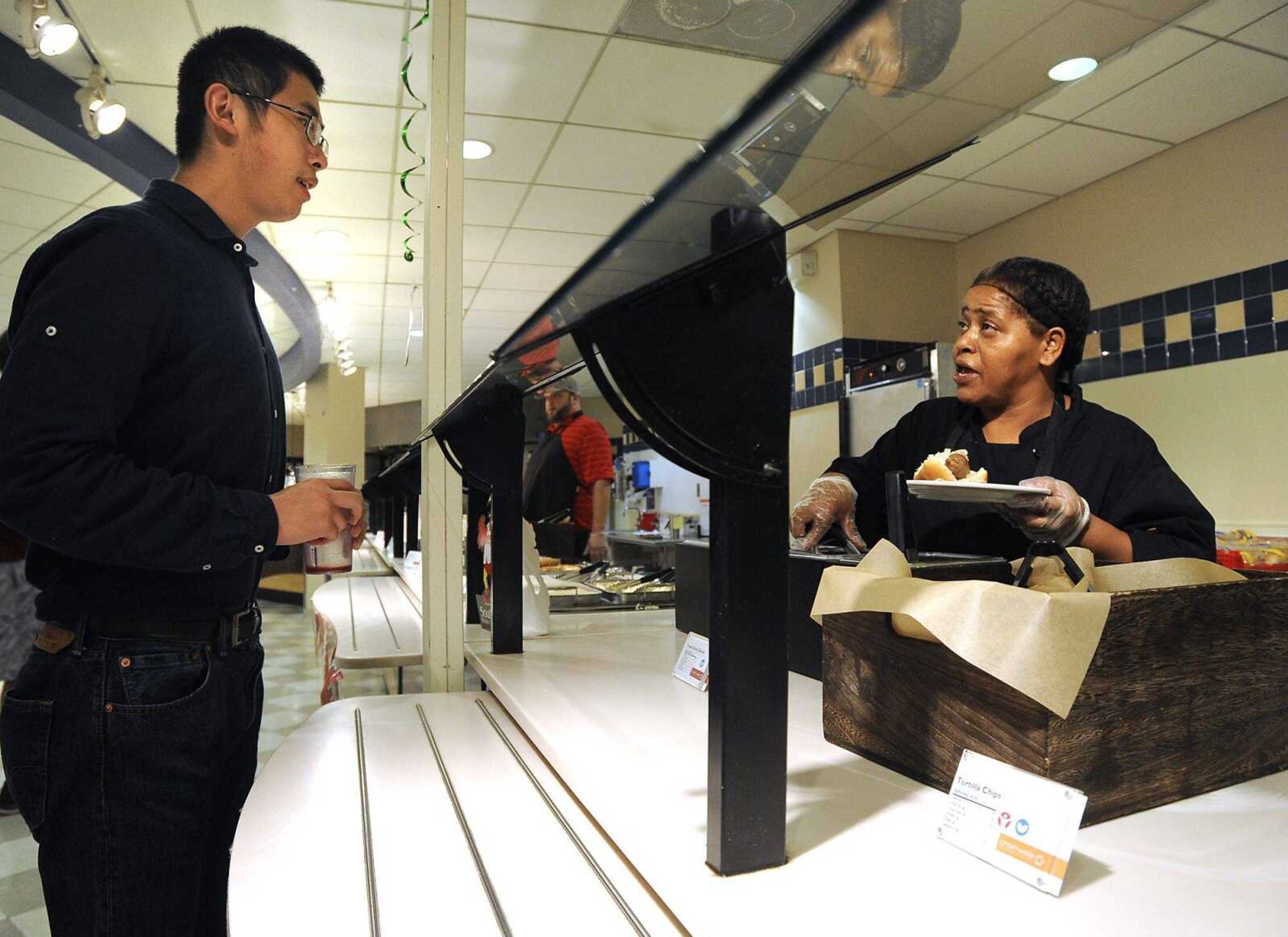 Chartwells server Tamra Nunley prepares a hot dog for Mingzhe Du during lunchtime Tuesday in the dining commons of Towers Complex at Southeast Missouri State University. (Fred Lynch)